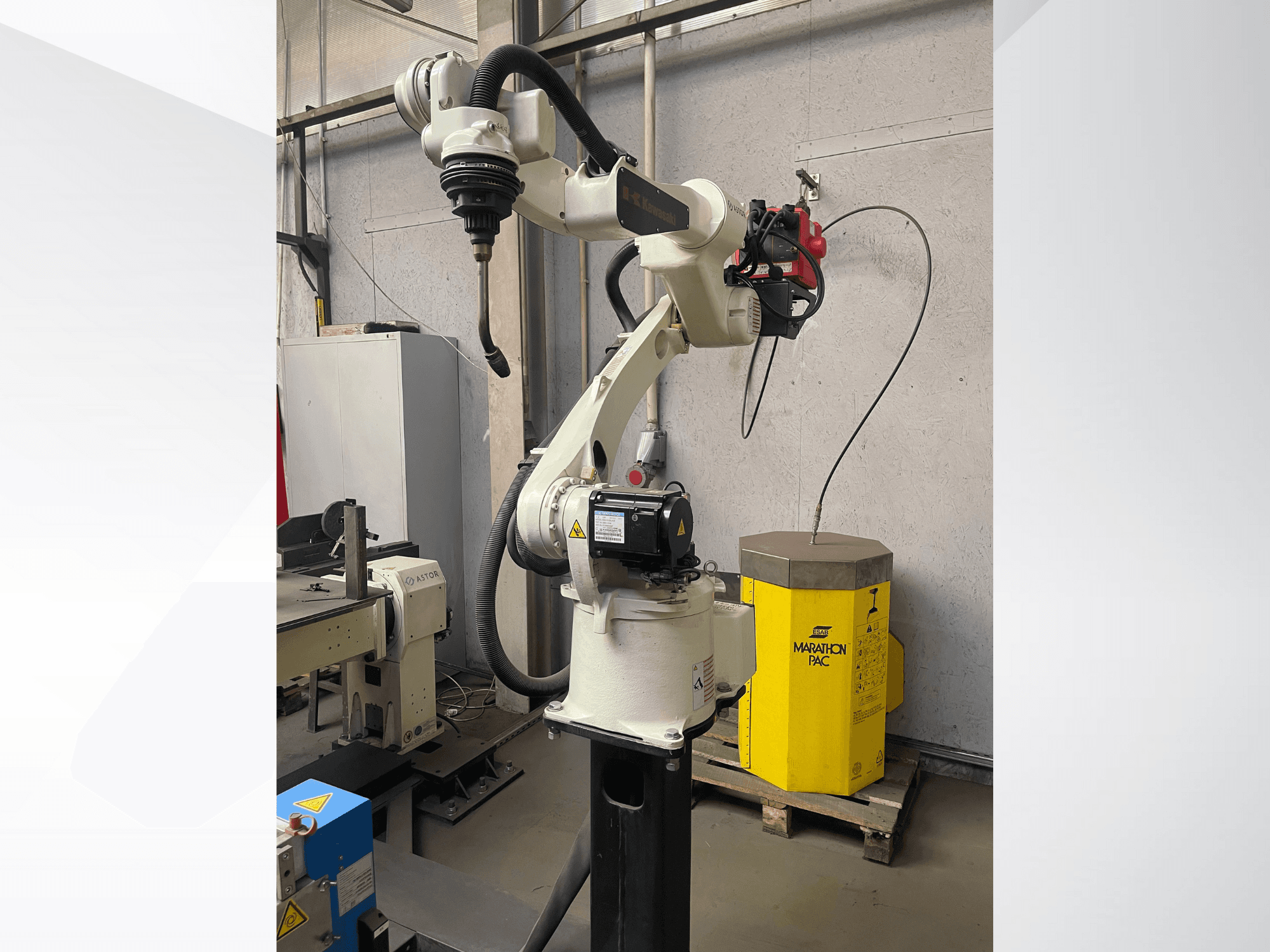 Kawasaki-Roboterarm in der Seitenansicht mit montiertem Werkzeughalter, im Hintergrund ein gelbes Aggregat.