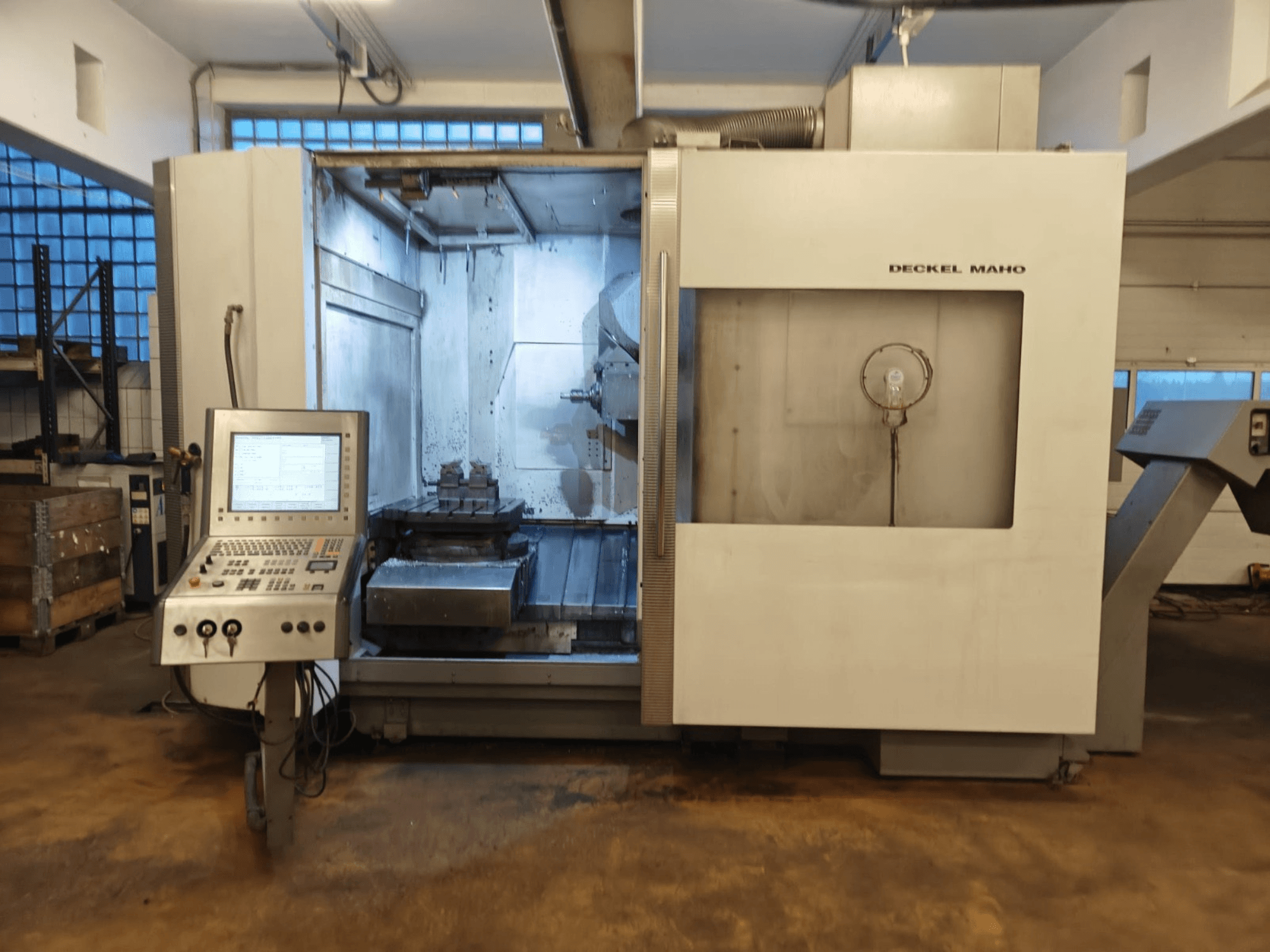 DECKEL MAHO DMC 60U Universal-Bearbeitungszentrum, Vorderansicht, mit Bedienfeld und Bearbeitungsraum mit Werkstückaufspannung.