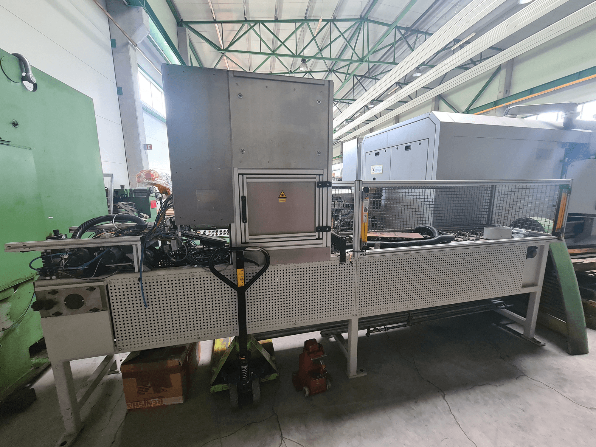 Industriemaschinen mit Metallrahmen, Schläuchen und Schalttafel, von der Seite gesehen in einer Fabrikumgebung.