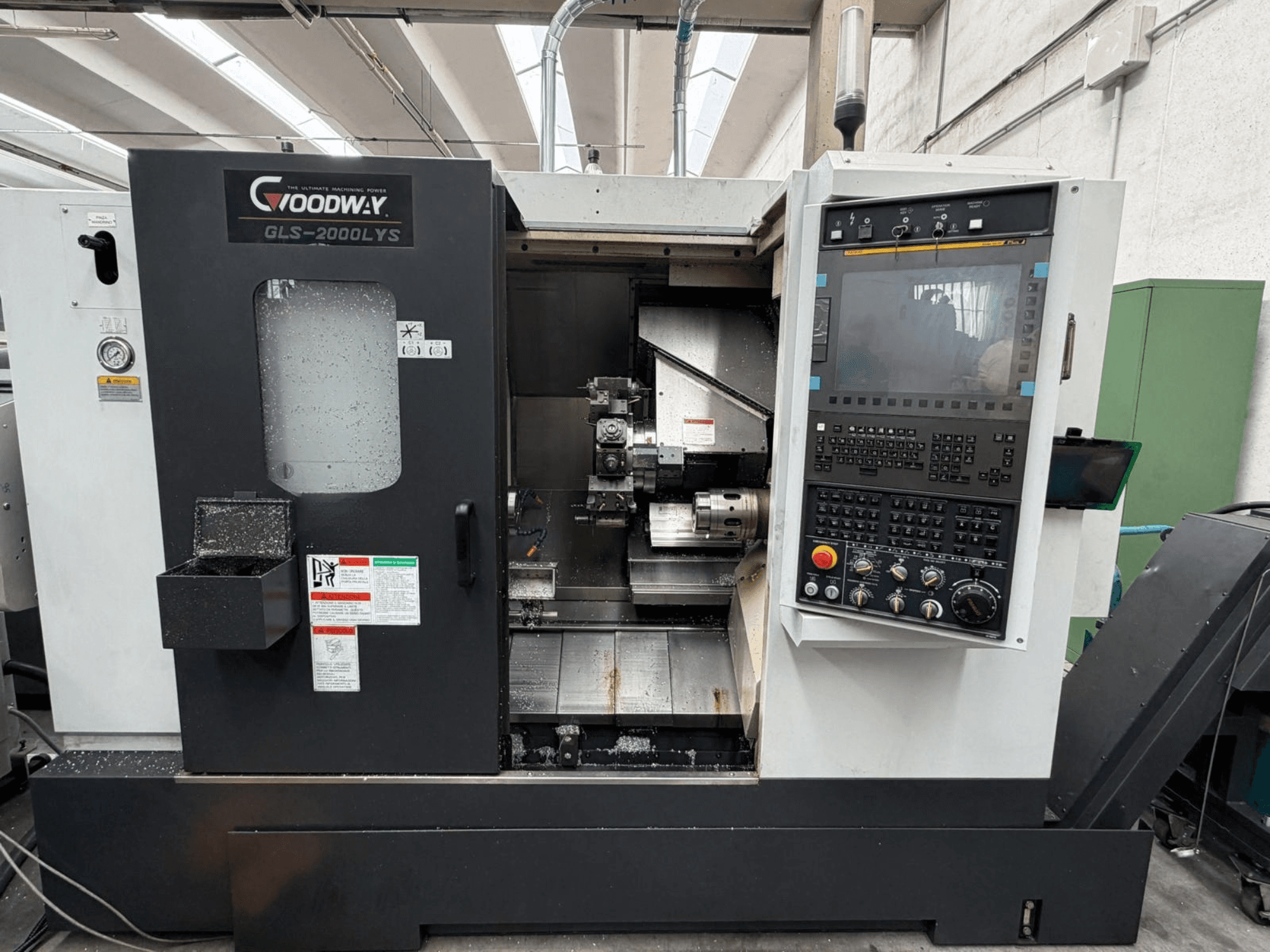 Die Horizontal-Drehmaschine Goodway GLS-2000LYS aus der Vorderansicht, mit Bedienfeld und sichtbaren Metallspänen.