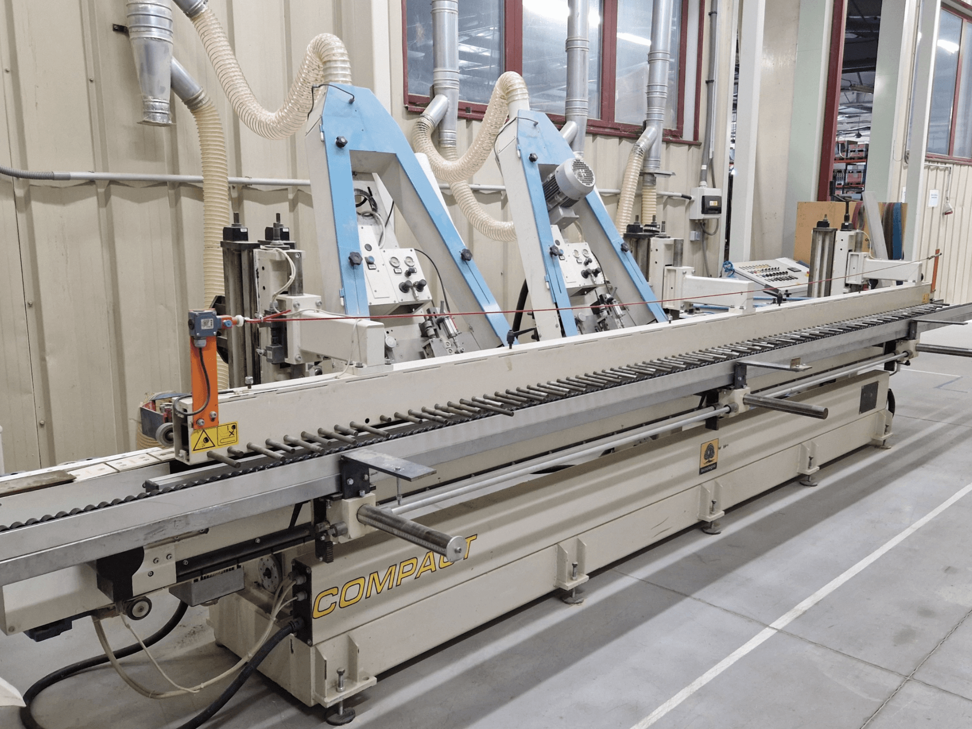 Bandschleifmaschine TECNOLEGNO COMPACT 52 in einer Werkstatt, mit Bedienfeld und Schleifbandmechanismus in der Seitenansicht.