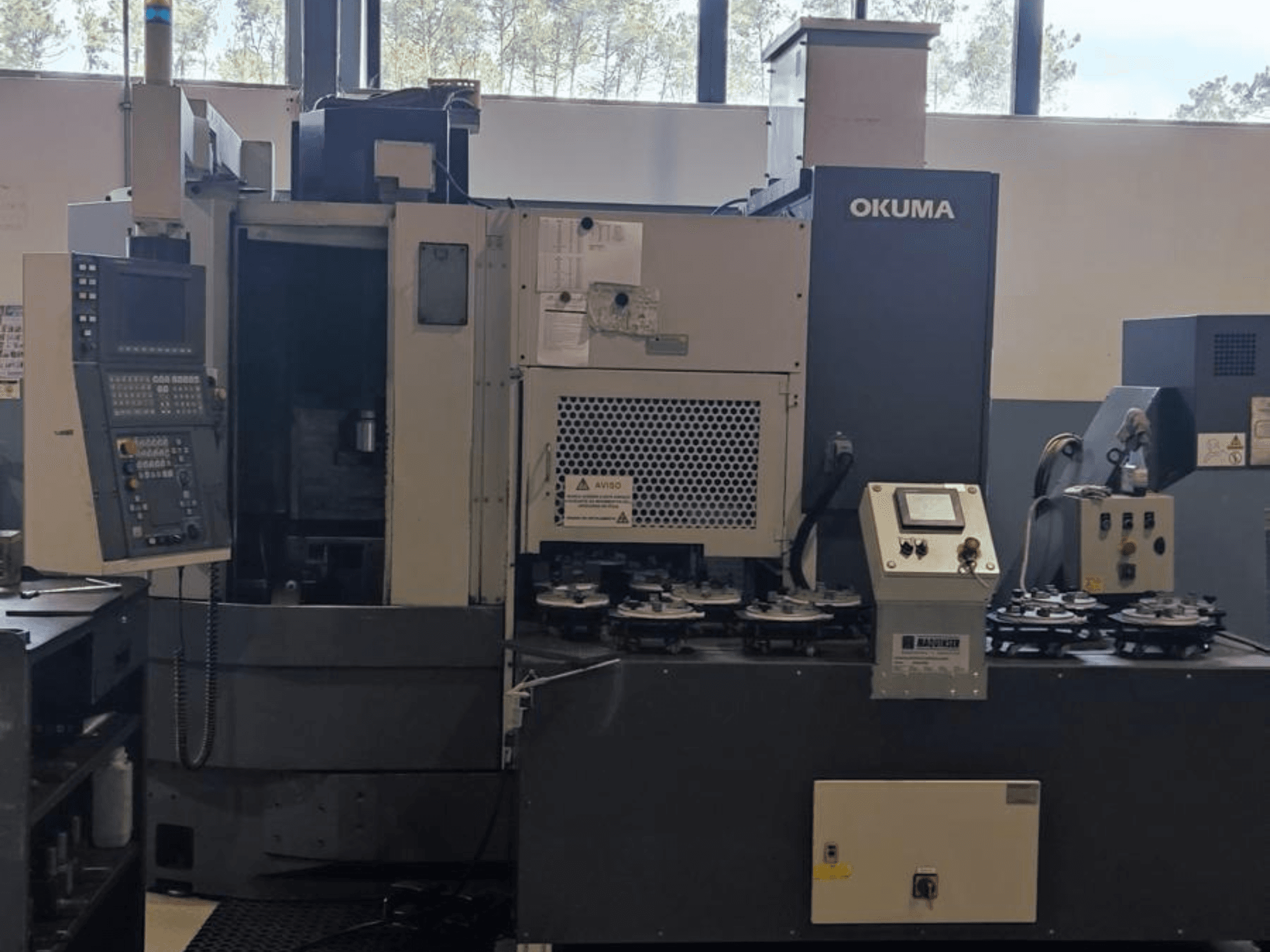 Okuma LVT300 Vertikaldrehmaschine in der Frontansicht mit Bedienfeld, Werkzeughaltern und Bearbeitungsbereich.