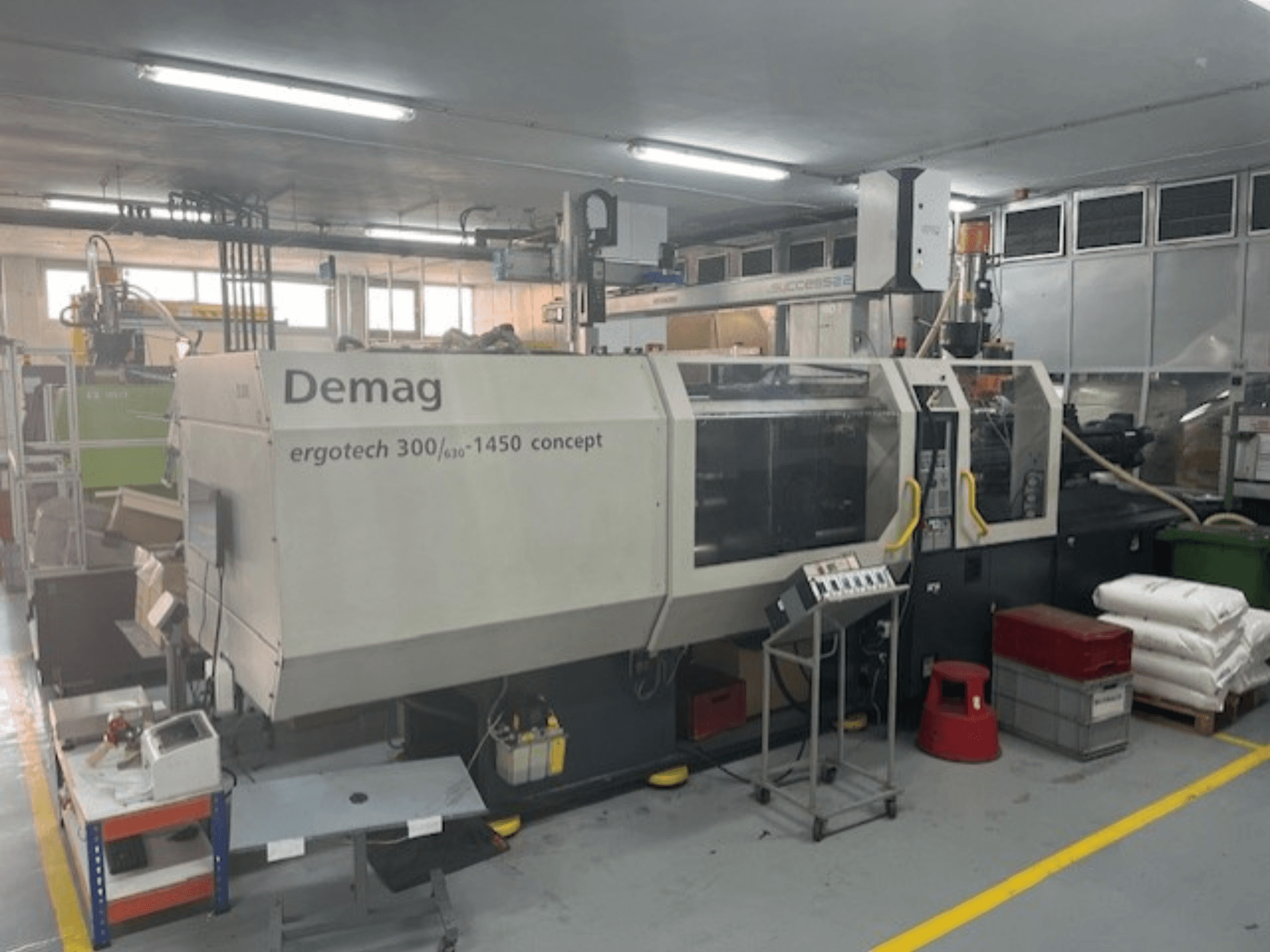 Demag ERGOTECH CONCEPT 3000-1450 hydraulische Spritzgießmaschine, Vorderansicht, mit Bedienelementen und Materialien in der Nähe.