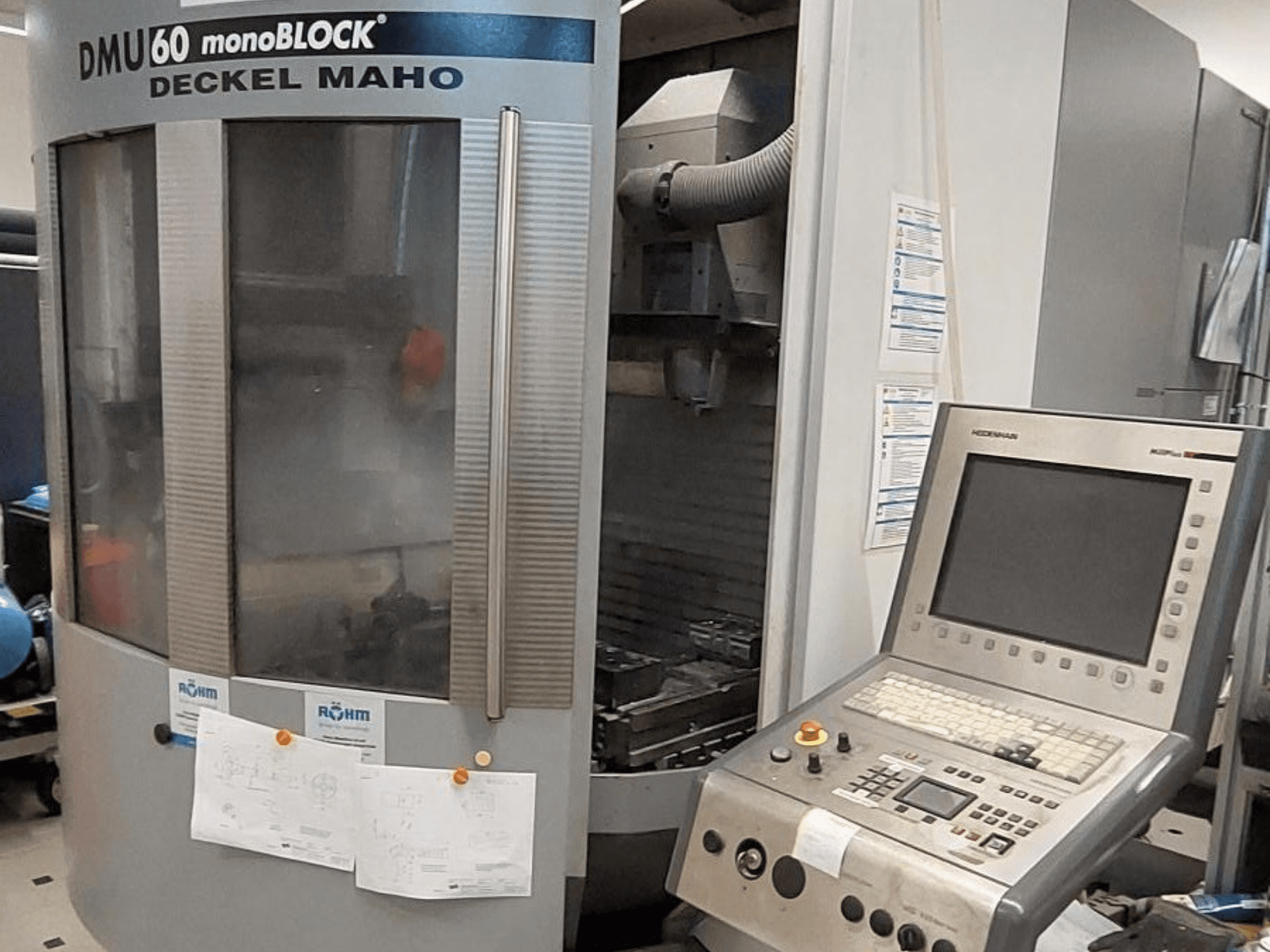 DMU 60 monoBLOCK von Deckel Maho, Frontansicht einer CNC-Fräsmaschine mit einem Bedienfeld und technischen Zeichnungen.