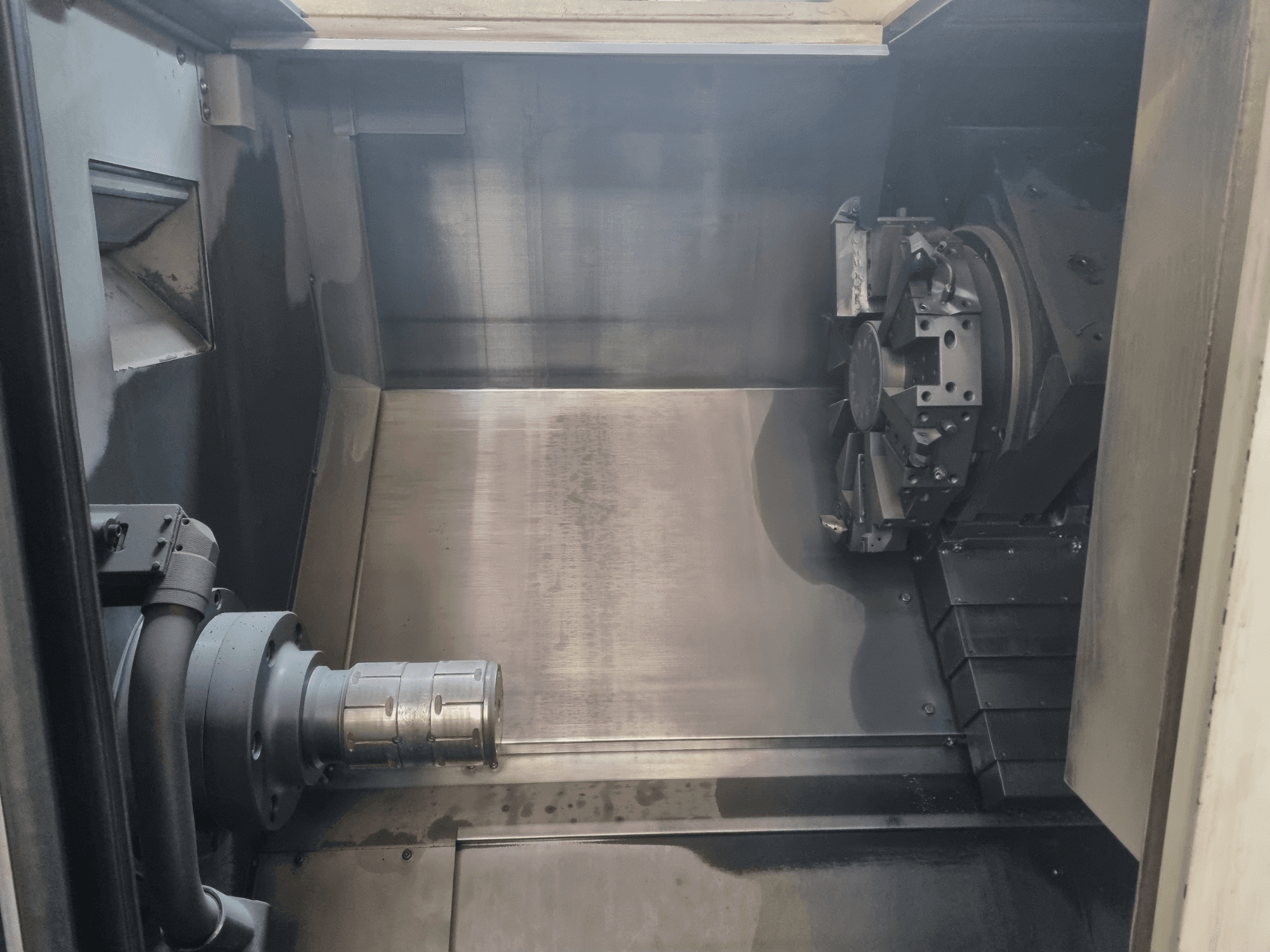 Innenansicht einer CNC-Maschine, die einen Metallarbeitsbereich, einen Werkzeughalter und ein Spannfutter zeigt; betont die Präzisionstechnik.