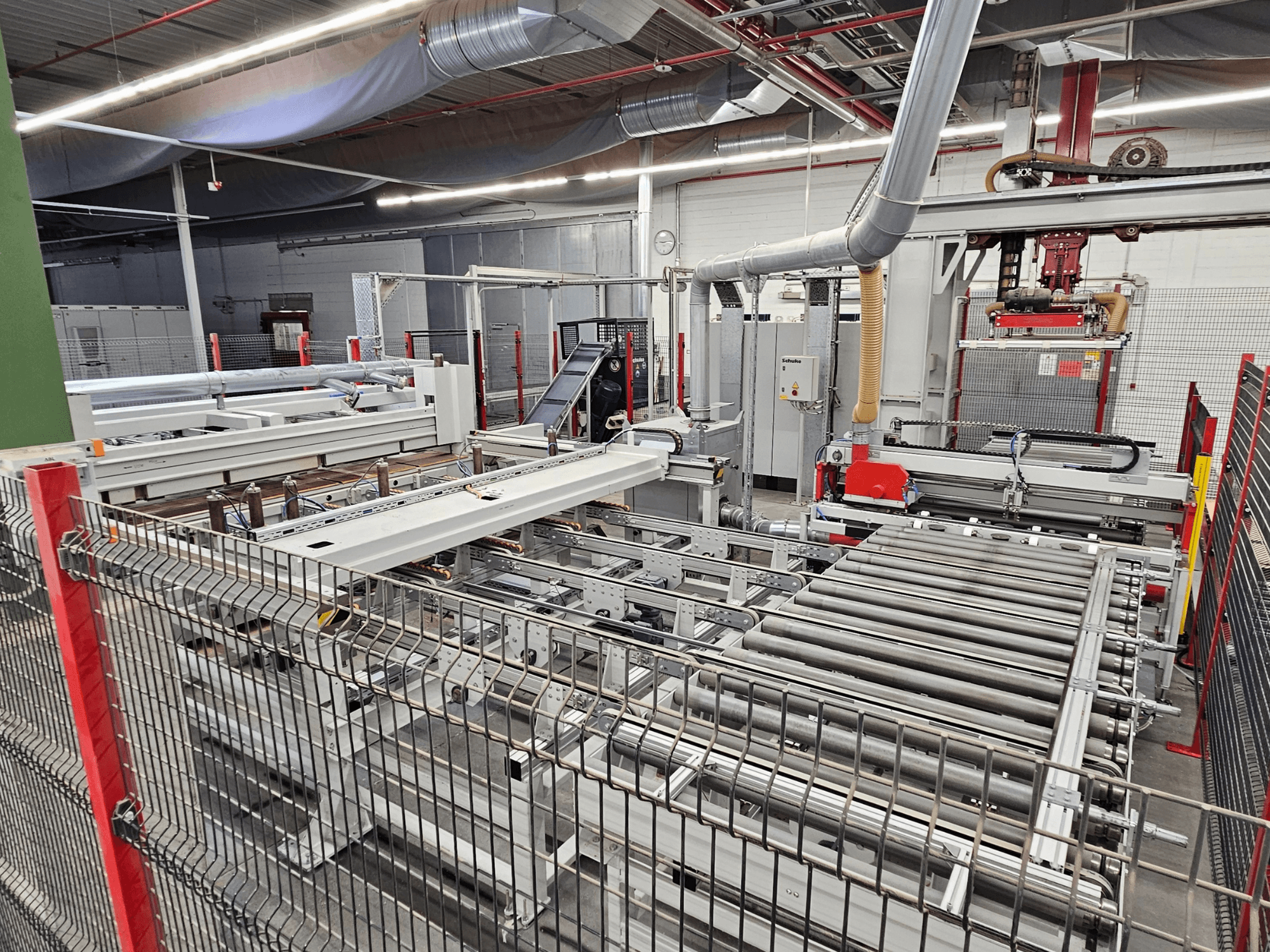 HOLZMA HPP81-3200 Plattensäge in der Frontansicht mit Förderrollen und Maschinenkomponenten in einer Werkstattumgebung.