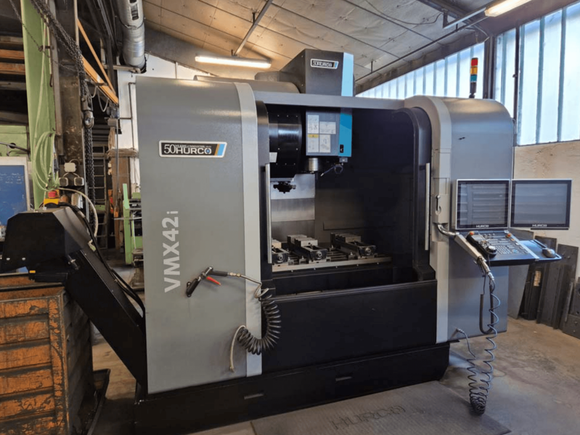 Hurco VMX 42i Vertikal-Bearbeitungszentrum, Vorderansicht, mit Bedienfeld und Arbeitsbereich mit Schraubstöcken.