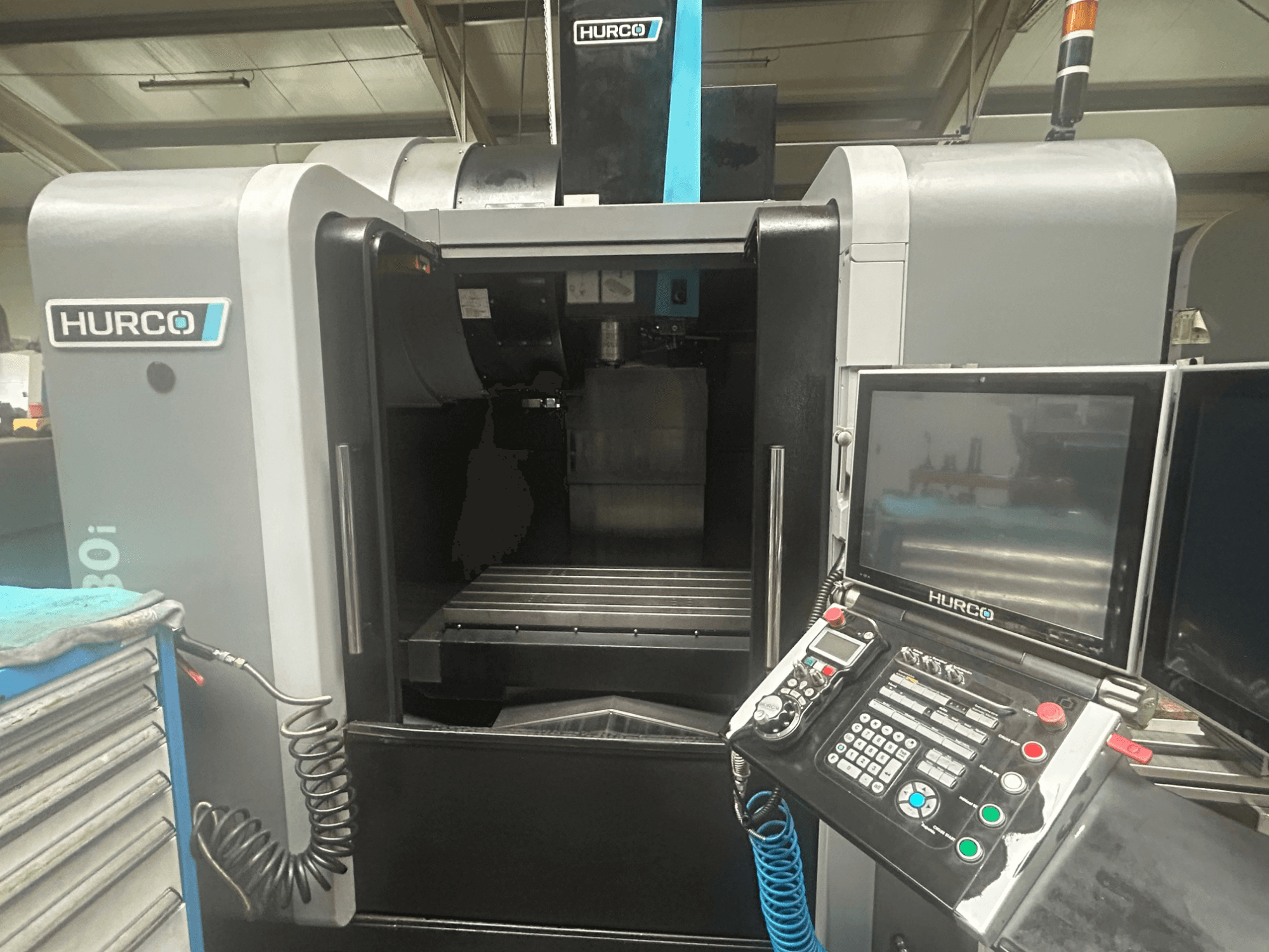 Vorderansicht der Hurco VM30i CNC-Maschine, mit Bedienfeld mit Tasten, Display und Werkzeugablagefläche.