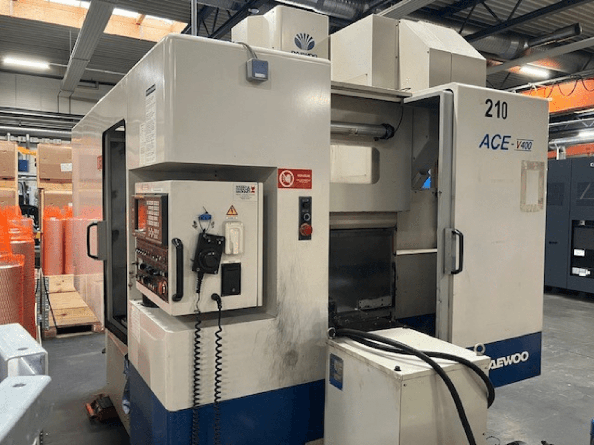 Daewoo ACE-V400 CNC-Maschine in der Seitenansicht, mit Bedienfeld, Kühlmitteltank und offenem Arbeitsbereich.