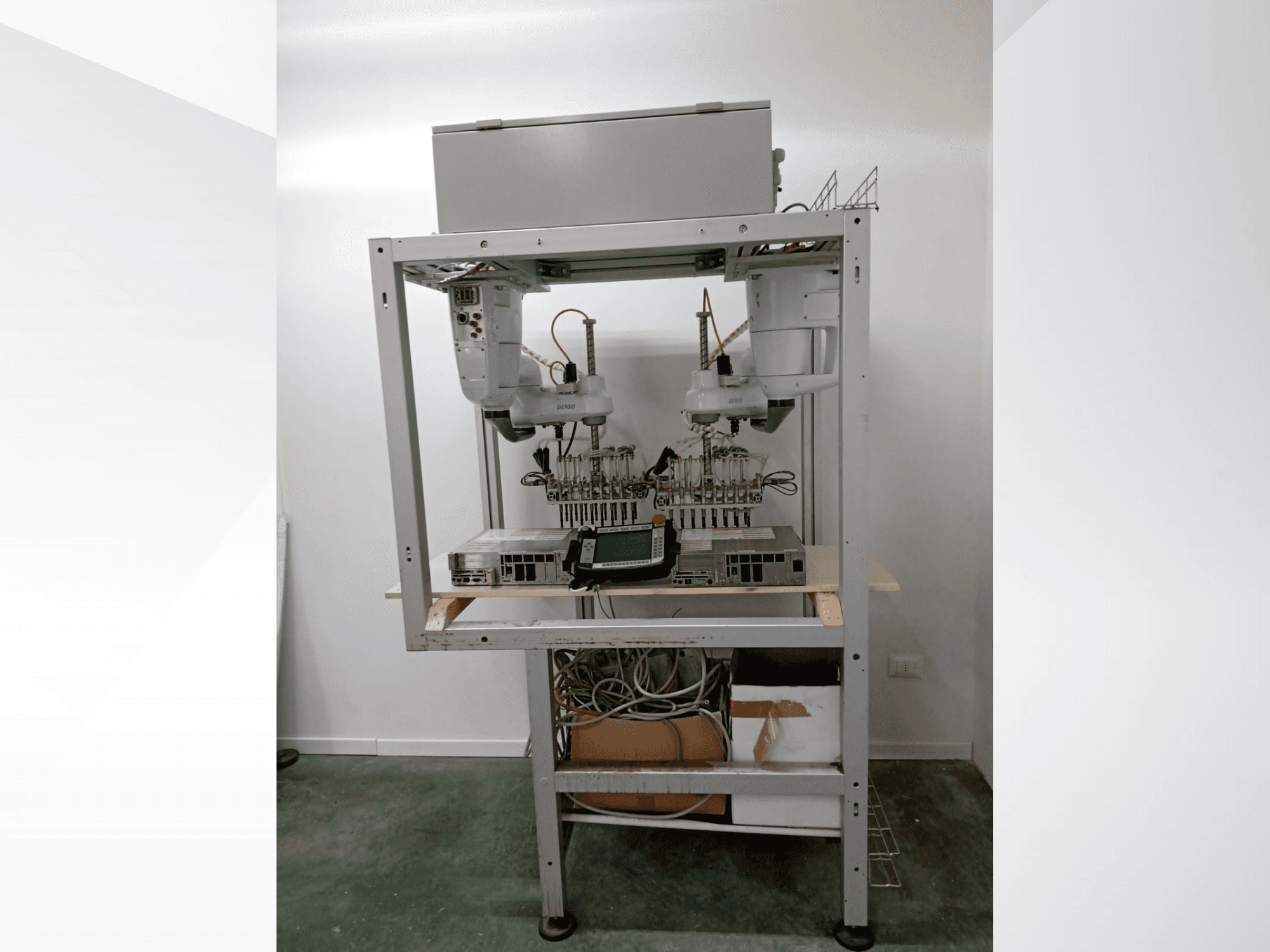 Automatisierter Roboterarbeitsplatz mit zwei Armen, Anzeigeeinheit und Elektronik auf einem Metallrahmen, Vorderansicht, fortschrittlicher Technologieaufbau.