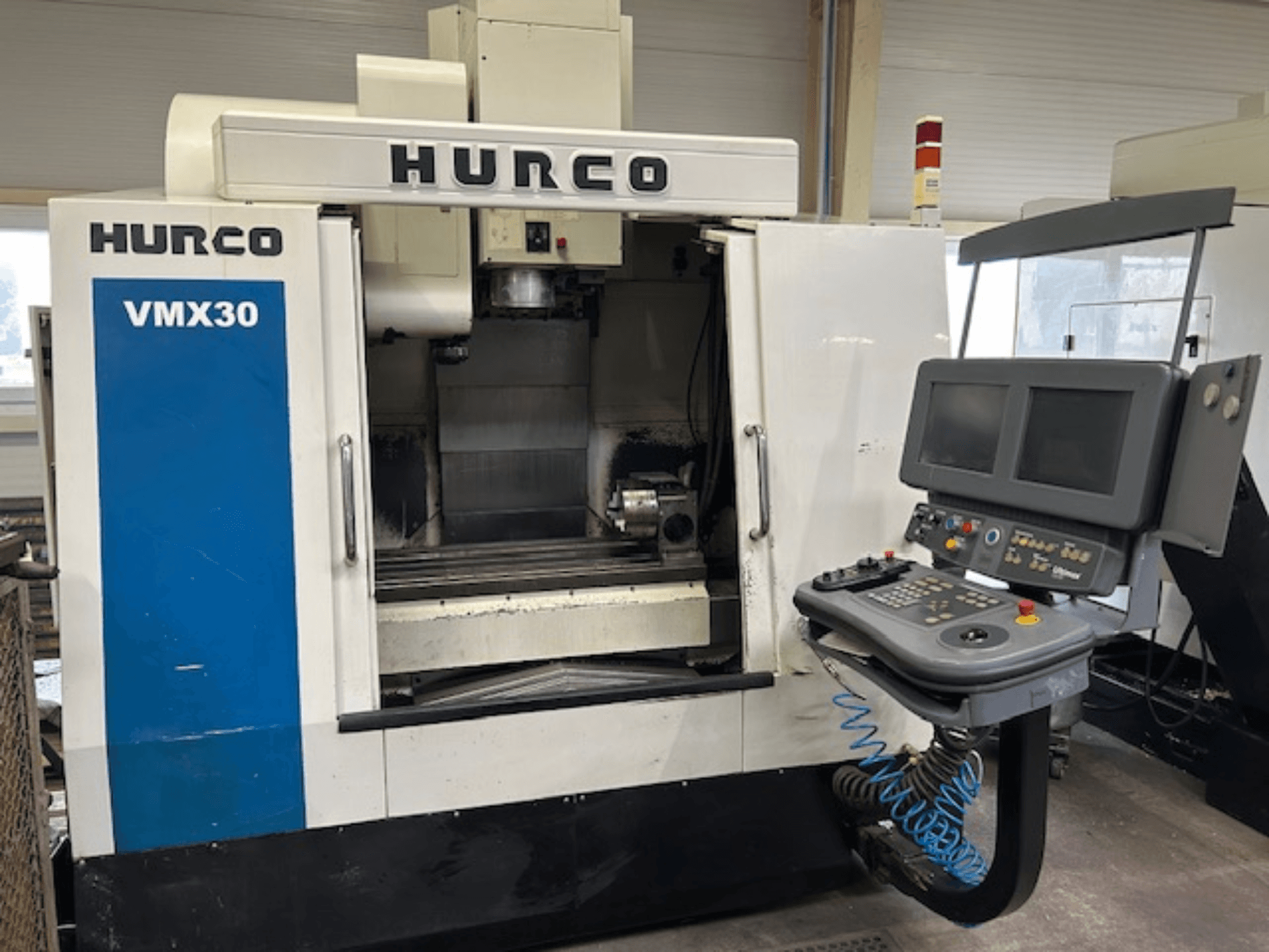 Hurco VMX30 CNC-Fräsmaschine in einer Werkstatt, Vorderansicht; mit Bedienfeld mit zwei Bildschirmen und Bedientasten.