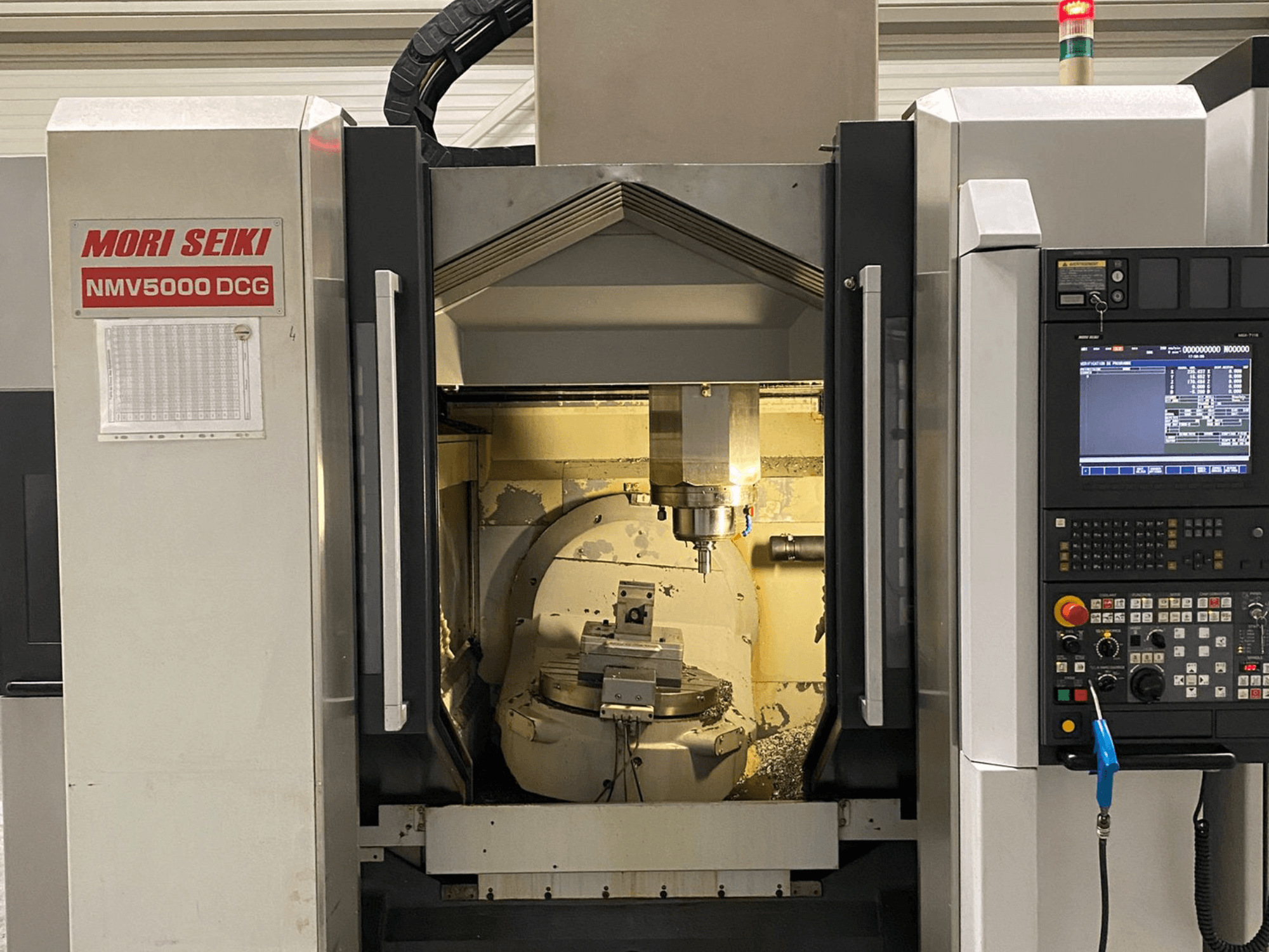 MORI SEIKI NMV 5000DCG Universal-Bearbeitungszentrum, Vorderansicht mit Bedienfeld und Innenbearbeitungsbereich.
