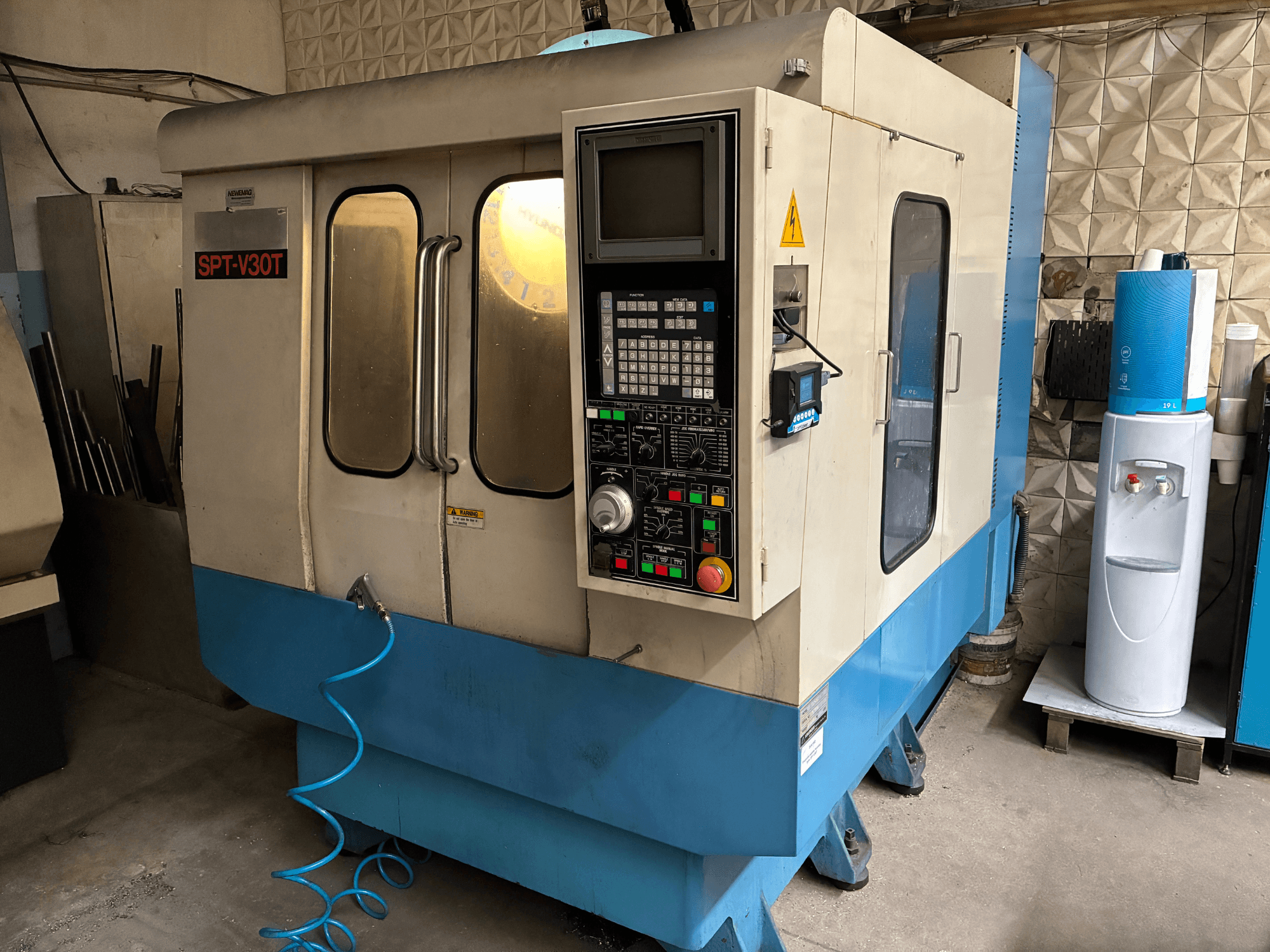 SPT-V30T CNC-Maschine in Blau und Weiß, Vorderansicht mit Bedienfeld, Türen und Luftschlauch. Perfekt für die Präzisionsbearbeitung.