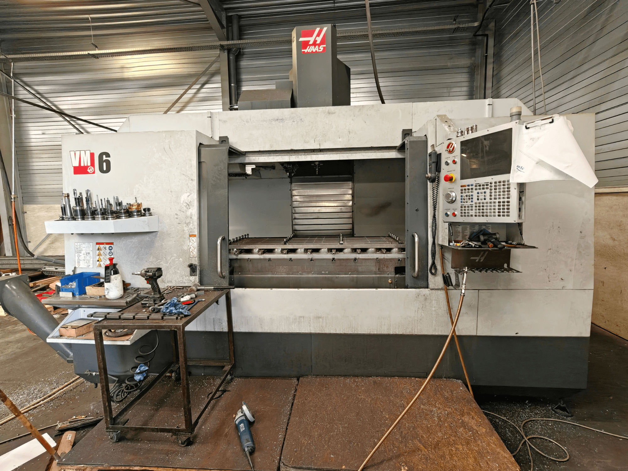 Vertikales Bearbeitungszentrum Haas VM-6, Vorderansicht, mit sichtbarem Werkzeugmagazin, Bedienfeld und Spänen im Arbeitsbereich.