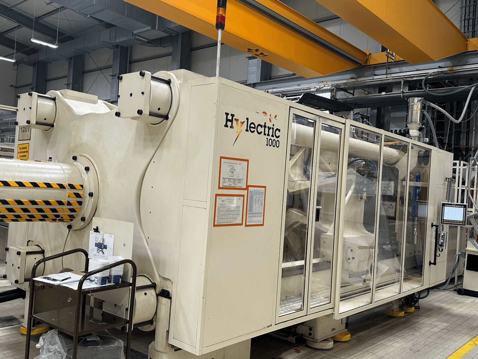 Elektrische Spritzgießmaschine Husky Hylelectric H1000 RS95/80, Seitenansicht mit sichtbarem Bedienfeld und Sicherheitsvorrichtungen.