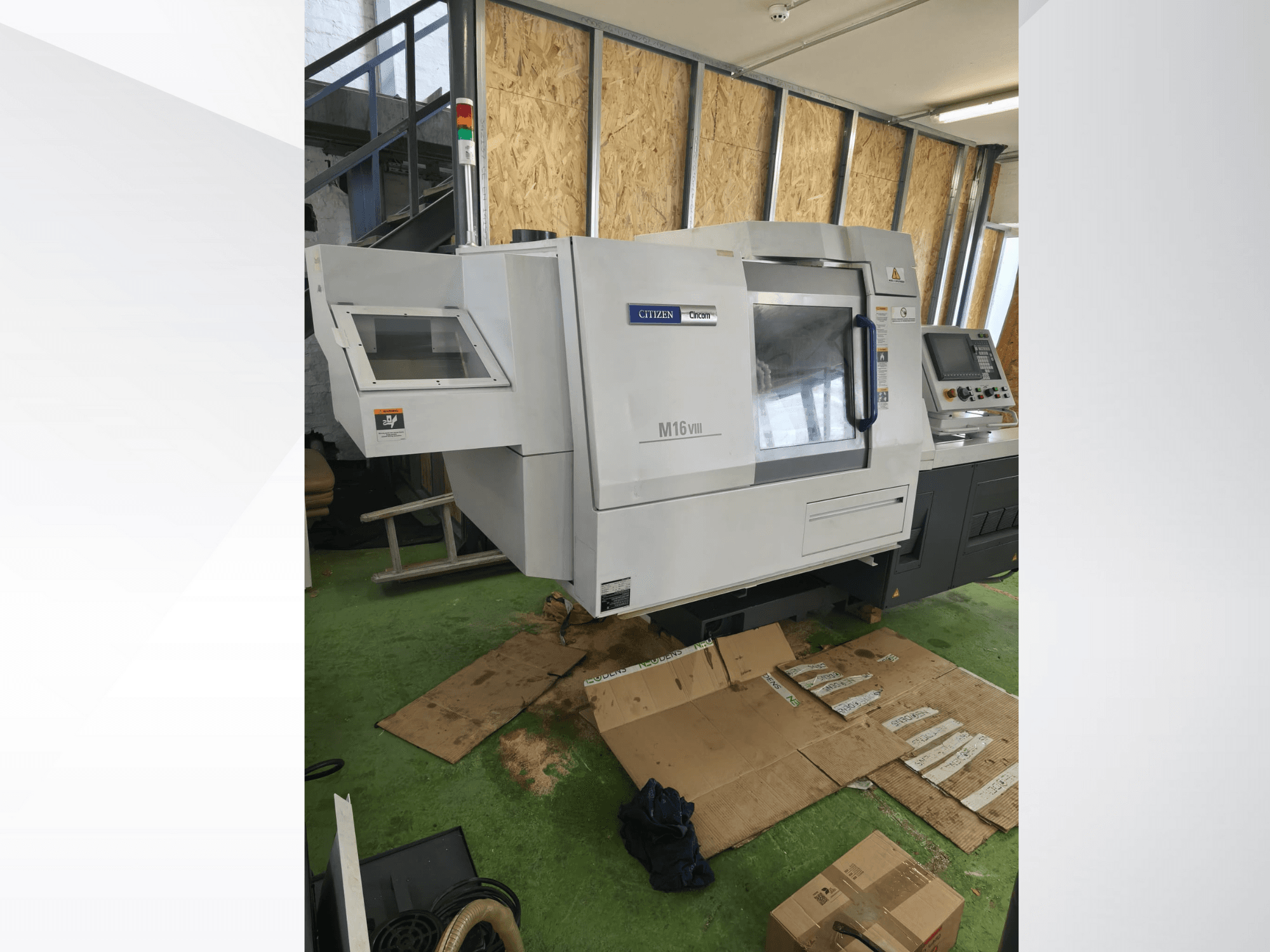 Citizen M16VIII CNC-Drehmaschine in Vorderansicht, mit Bedienfeld und Sicherheitswarnleuchten, auf grünem Boden.