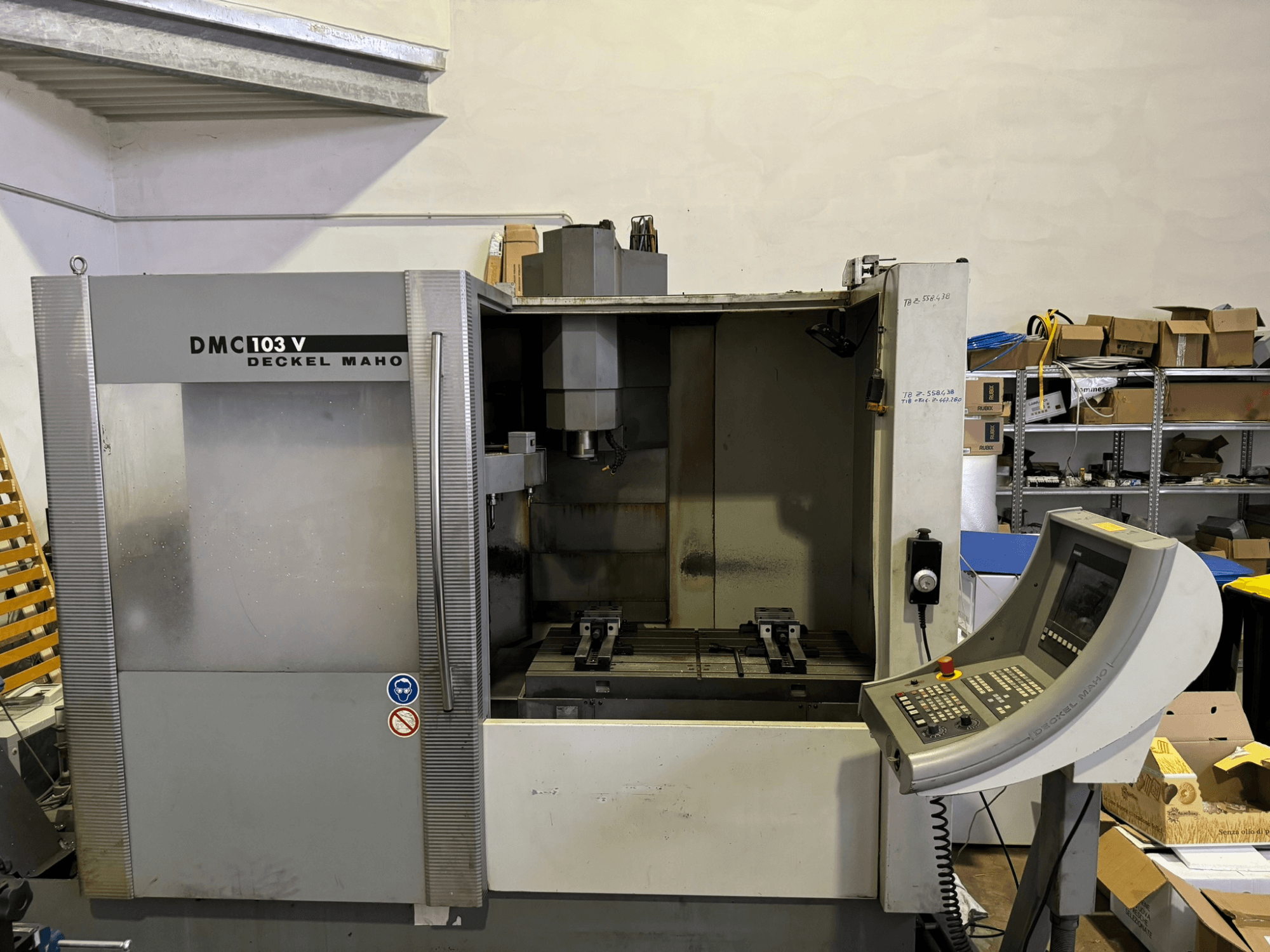 DMC 103 V Deckel Maho Fräsmaschine, Vorderansicht, zeigt Bedienfeld, Metallteile und Lagerbereich im Hintergrund.
