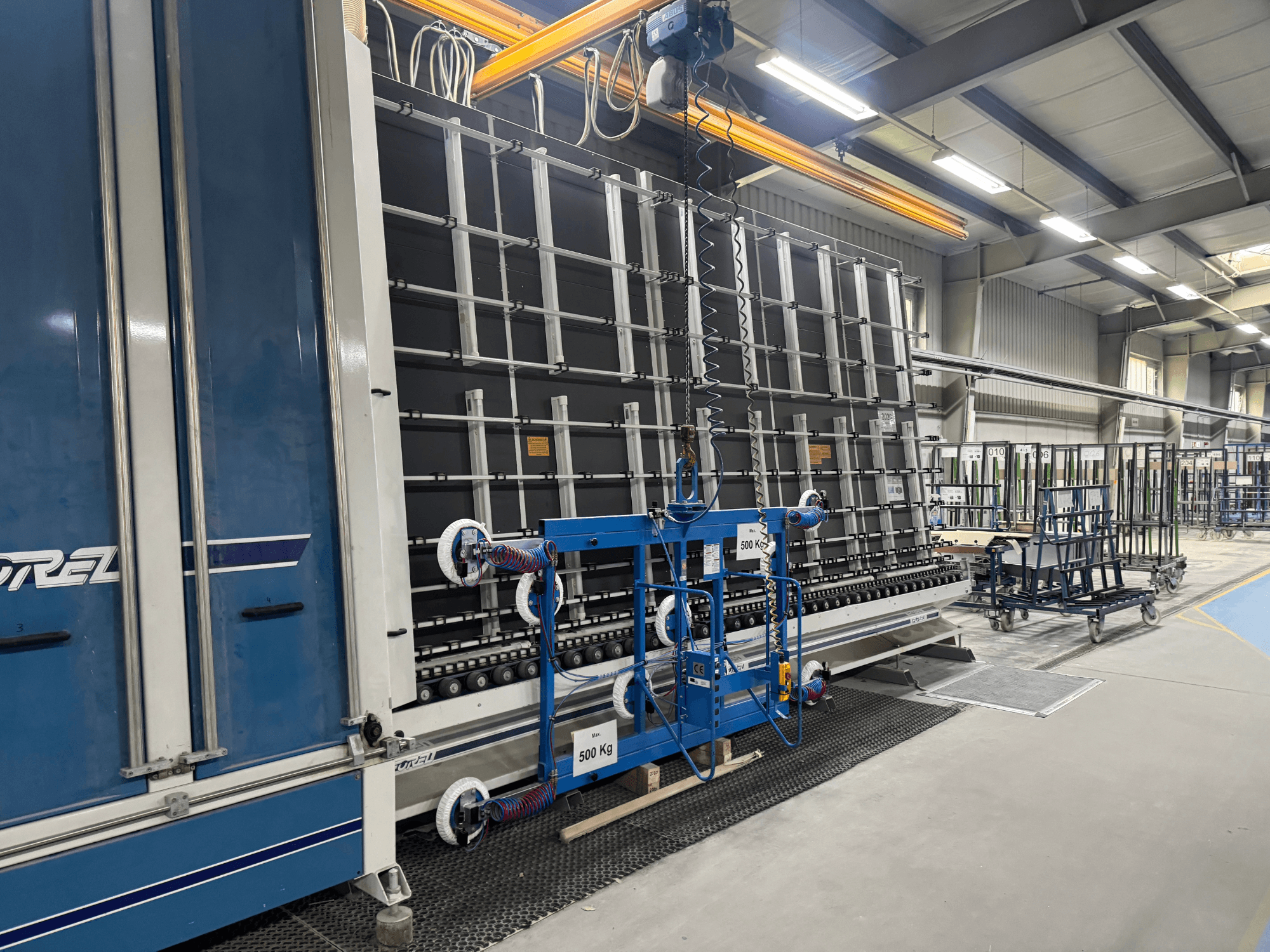 Industrielle Ausrüstung von Drel mit einem großen Rahmen und einem Hebemechanismus, dargestellt in einer Seitenansicht in einer Fabrikumgebung.