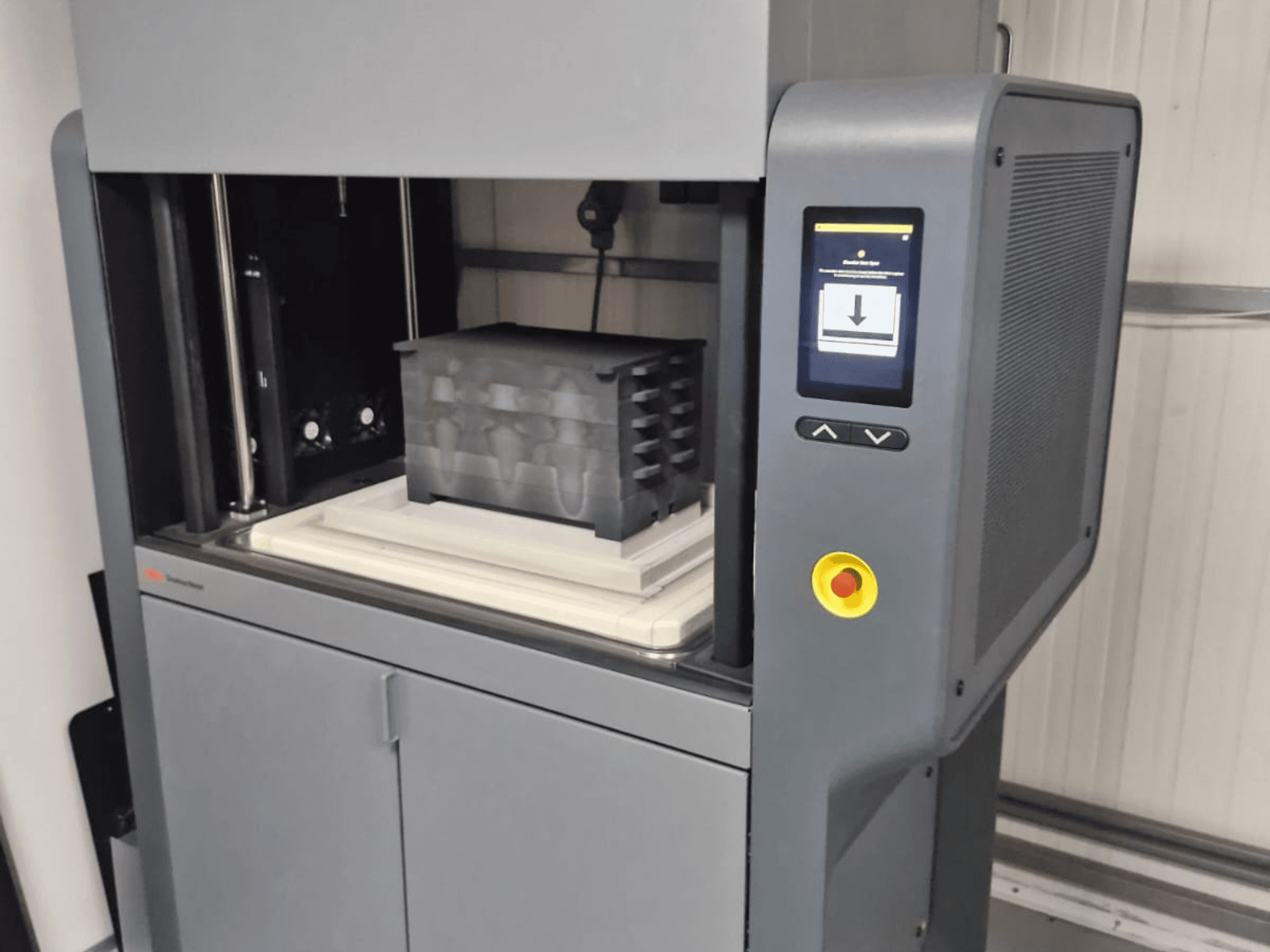 Metal Studio 2 3D-Drucker von Desktop Metal, Vorderansicht mit Bedienfeld und Druckbett mit schwarzem Behälter.