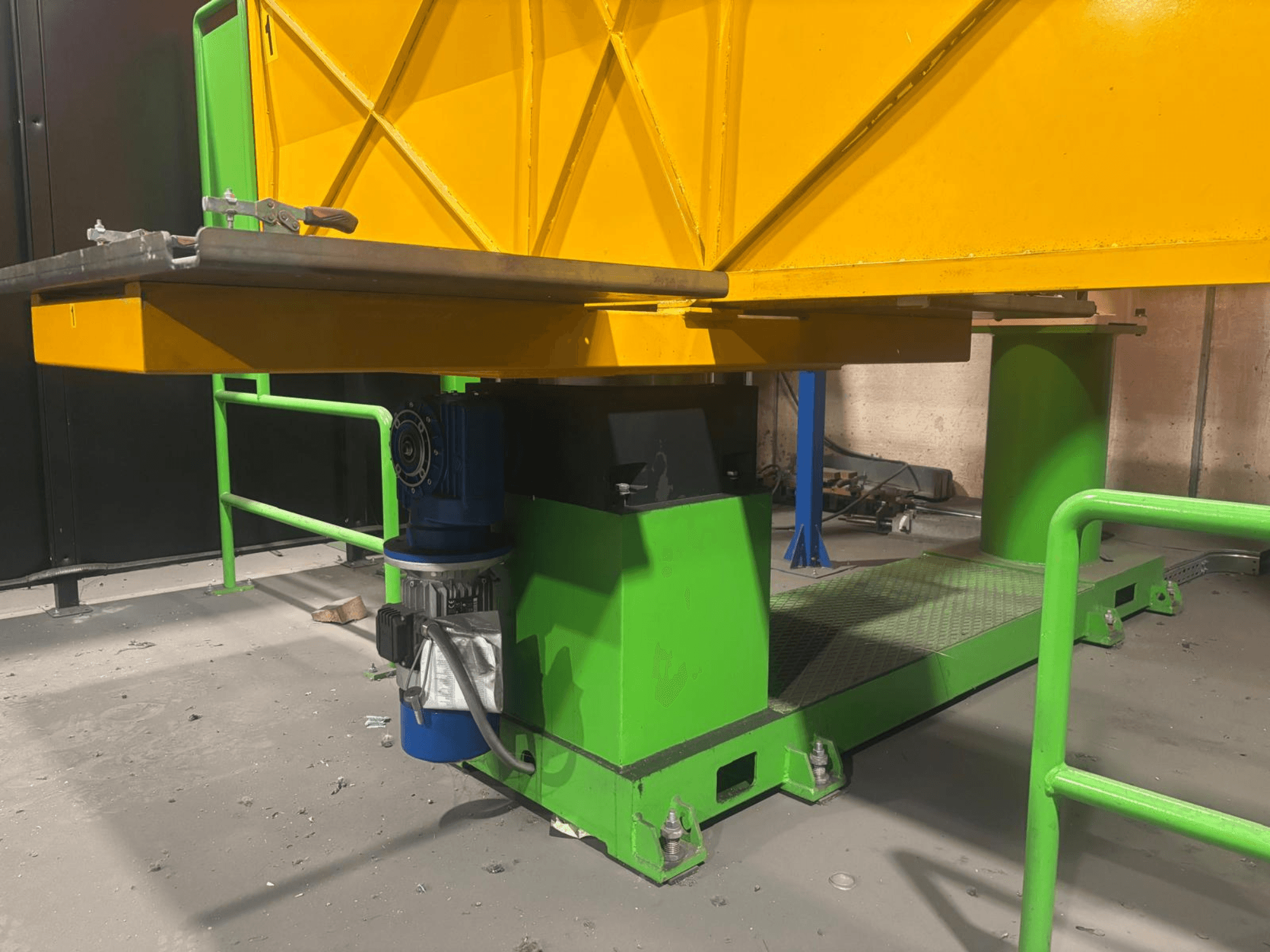 Grüne und gelbe Industriemaschinen mit Motor und Plattform mit strukturierter Oberfläche, von vorne gesehen.