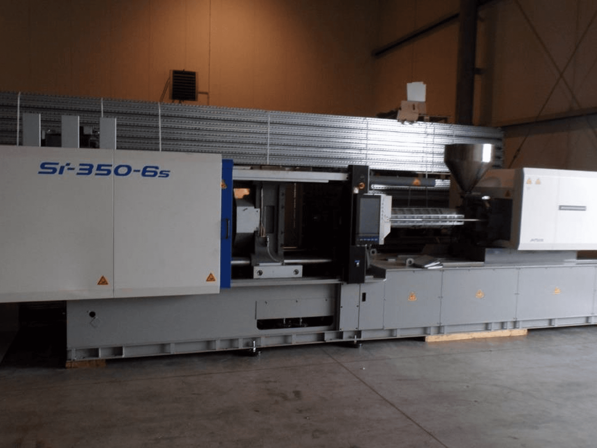 Spritzgießmaschine Si-350-6s in der Seitenansicht mit Trichter und Bedienfeld in einer großzügigen Industrieumgebung.