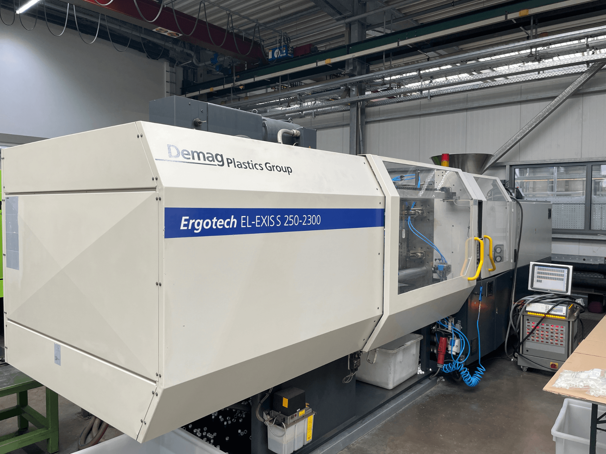 Demag Ergotech EL-EXIS S 250-2300 Spritzgießmaschine, Seitenansicht mit Bedienfeld und Zuführsystem.