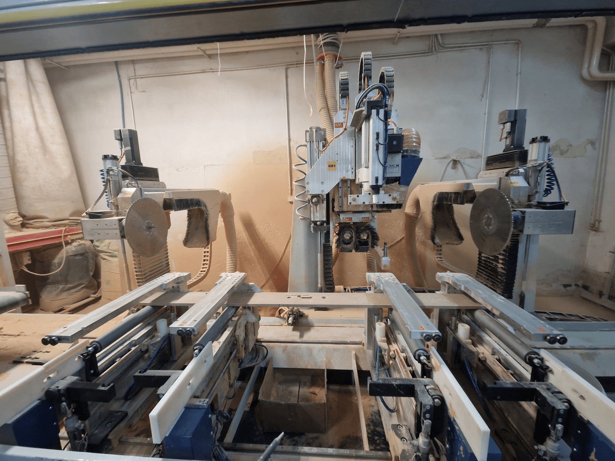 CNC-Maschine mit zwei Sägeblättern und Schienen, von vorne gesehen. Staubabsaugung sichtbar, geeignet für die Holzbearbeitung.