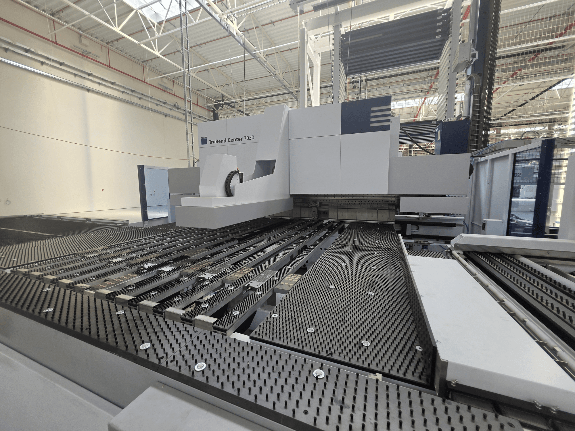 TRUMPF TruBend Center 7030 Abkantpresse in einer Fabrikumgebung, Vorderansicht mit dem komplex aufgebauten Arbeitstisch und dem Biegearm.