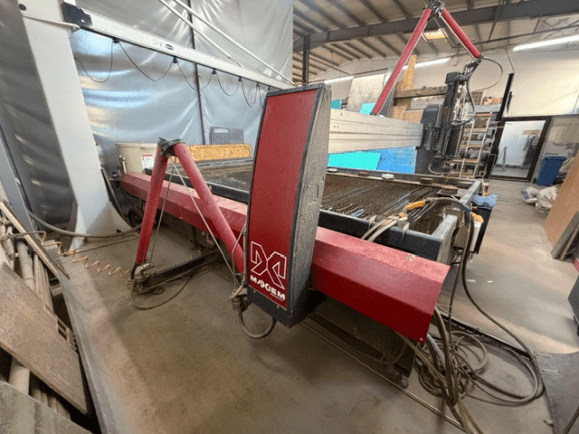 Rote Wasserstrahlschneidanlage der Marke X, von der Seite gesehen, mit mechanischen Komponenten und Rohrleitungsdetails.