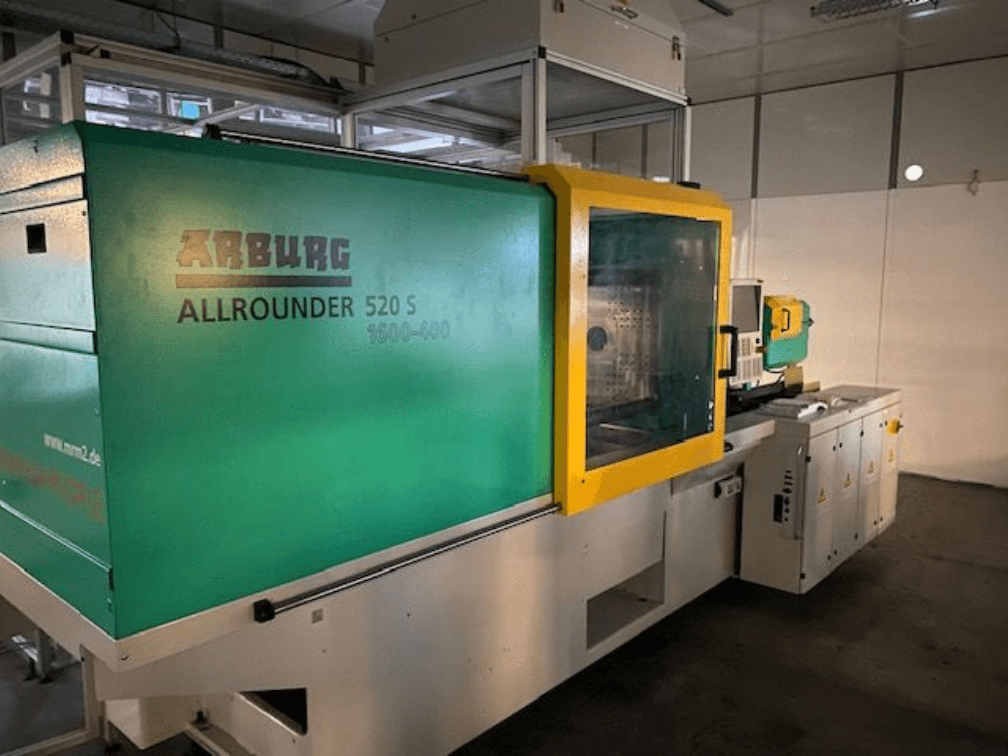 Arburg Allrounder 520 S Spritzgießmaschine, Seitenansicht, mit grün-gelbem Äußeren, technische Details sichtbar.