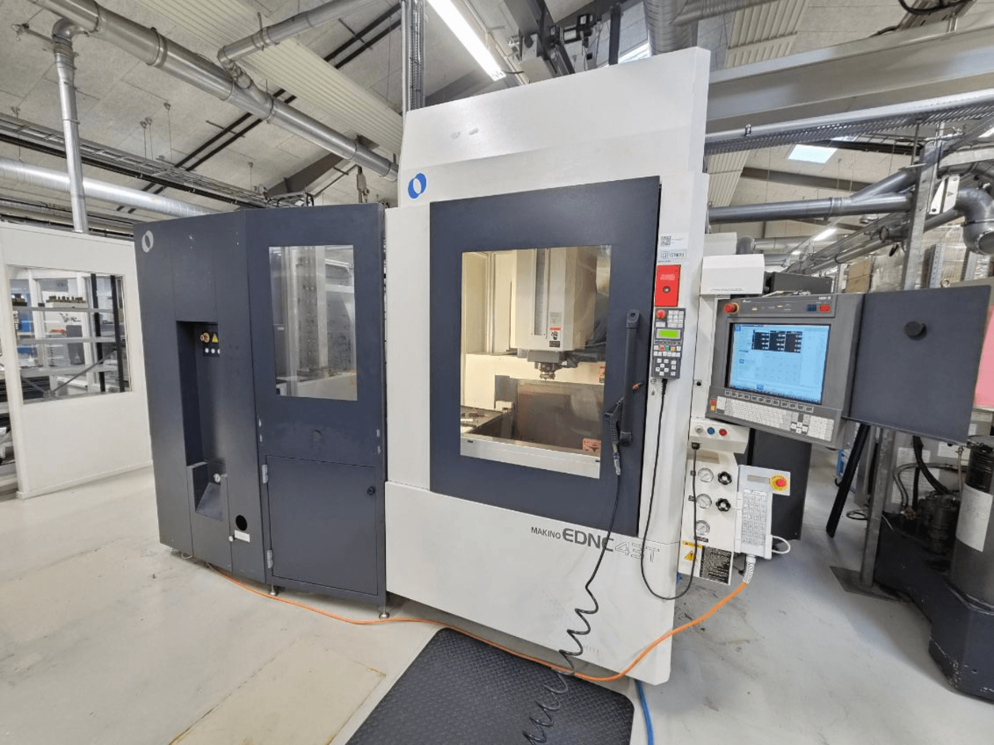 Vorderansicht einer Makino EDNC 43T Senk-Elektroerosionsmaschine mit Erowa-Roboter, Steuerung und sichtbarem Arbeitsbereich.