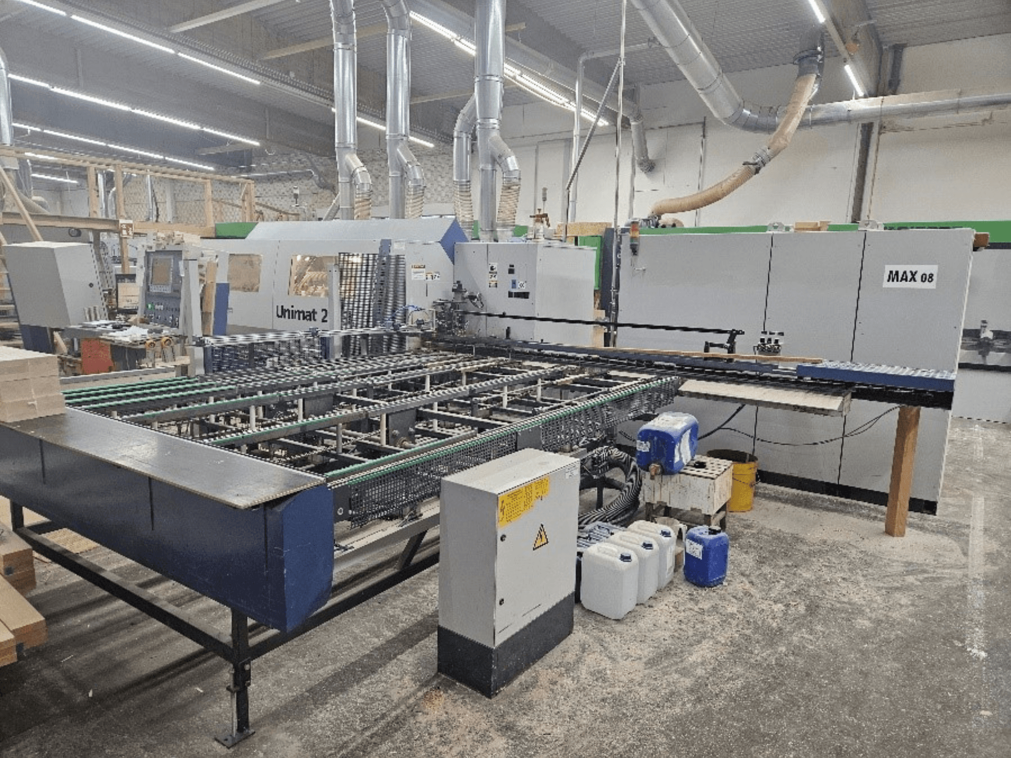 Seitenansicht einer Unimat 2 CNC-Maschine in einer Werkstatt, mit Förderbändern und technischen Komponenten mit sichtbarer Max 08-Einheit.