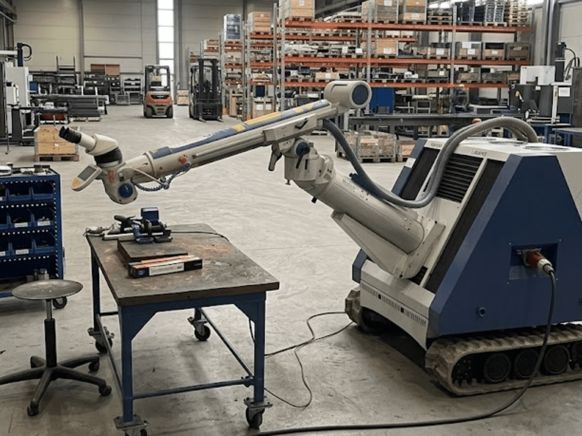 ALPHA LASER ALFlak300 M-Werkzeugmaschine in einer Werkstatt mit Roboterarm, Vorderansicht, die die präzise Aufspannung auf dem Arbeitstisch zeigt.