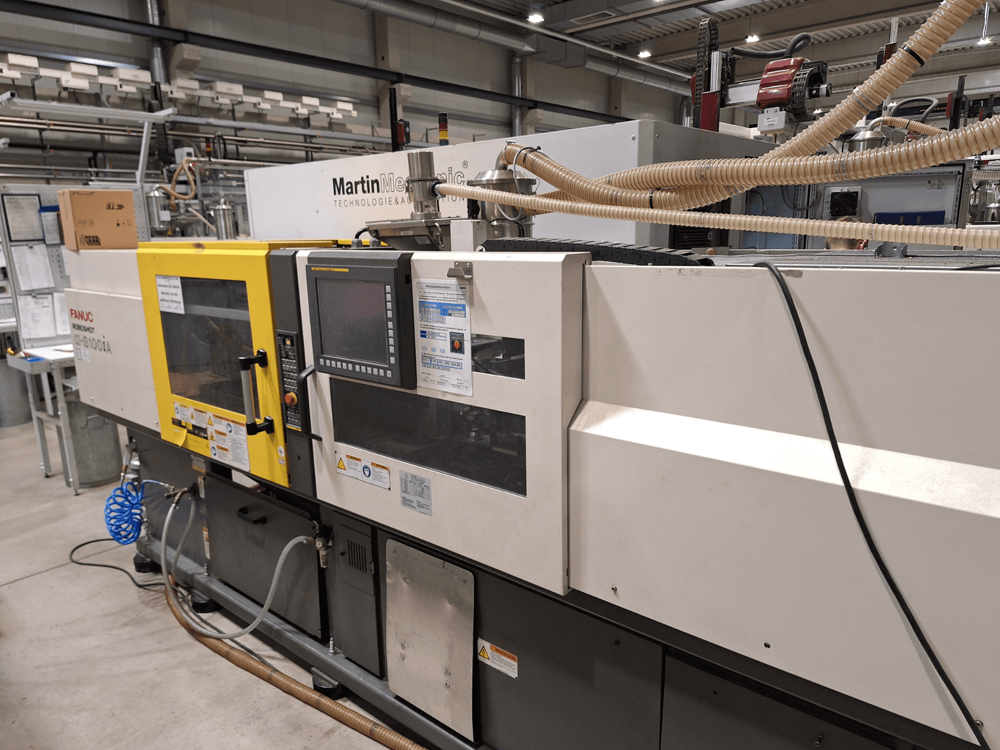 Elektrische Spritzgießmaschine FANUC Roboshot S100iA, Seitenansicht, ausgestattet mit Touchscreen und Sicherheitsetiketten.