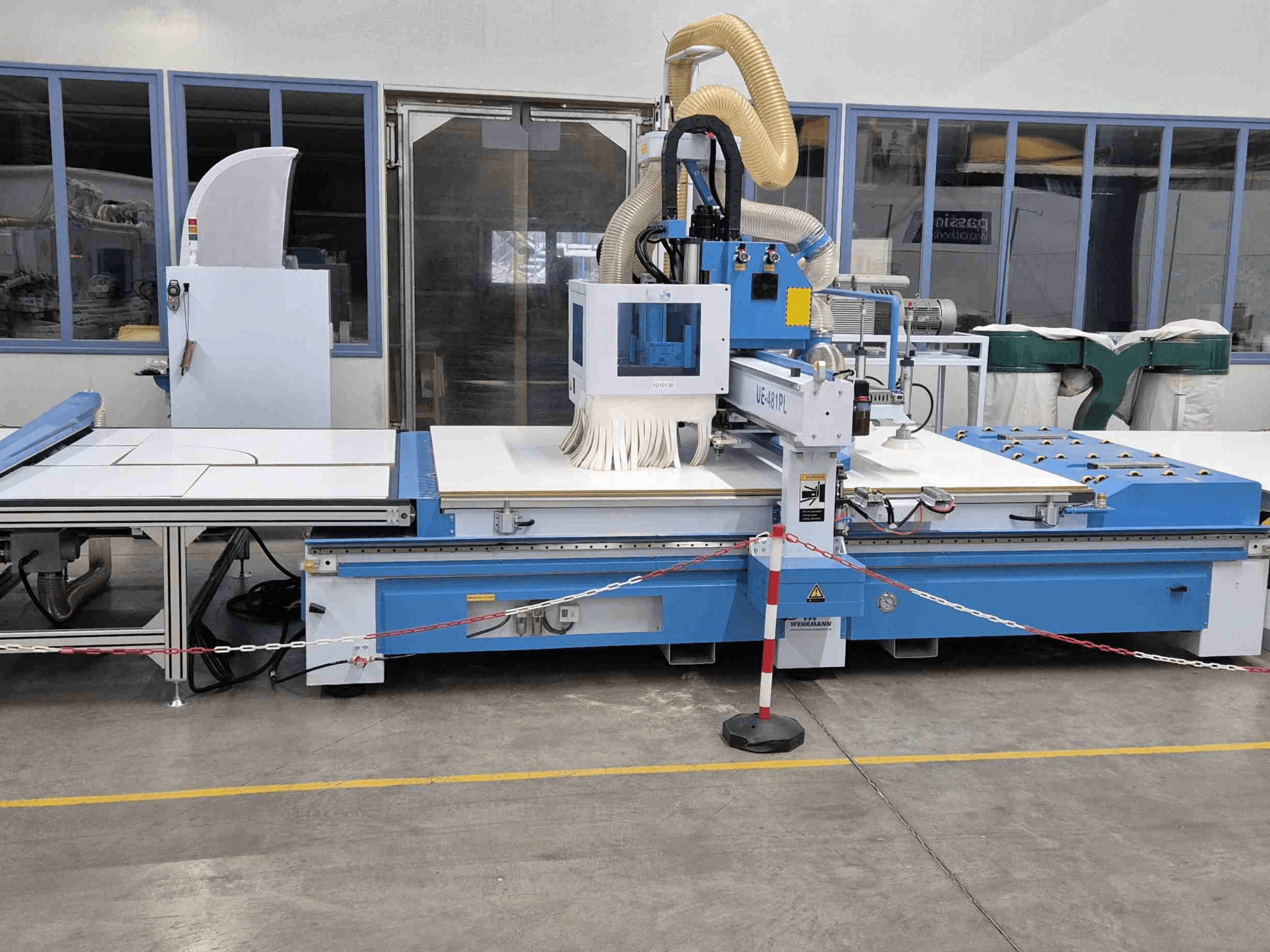 Blaue CNC-Oberfräse UE-621PL von vorne, mit großem Schneidtisch und angeschlossener Staubabsaugung.