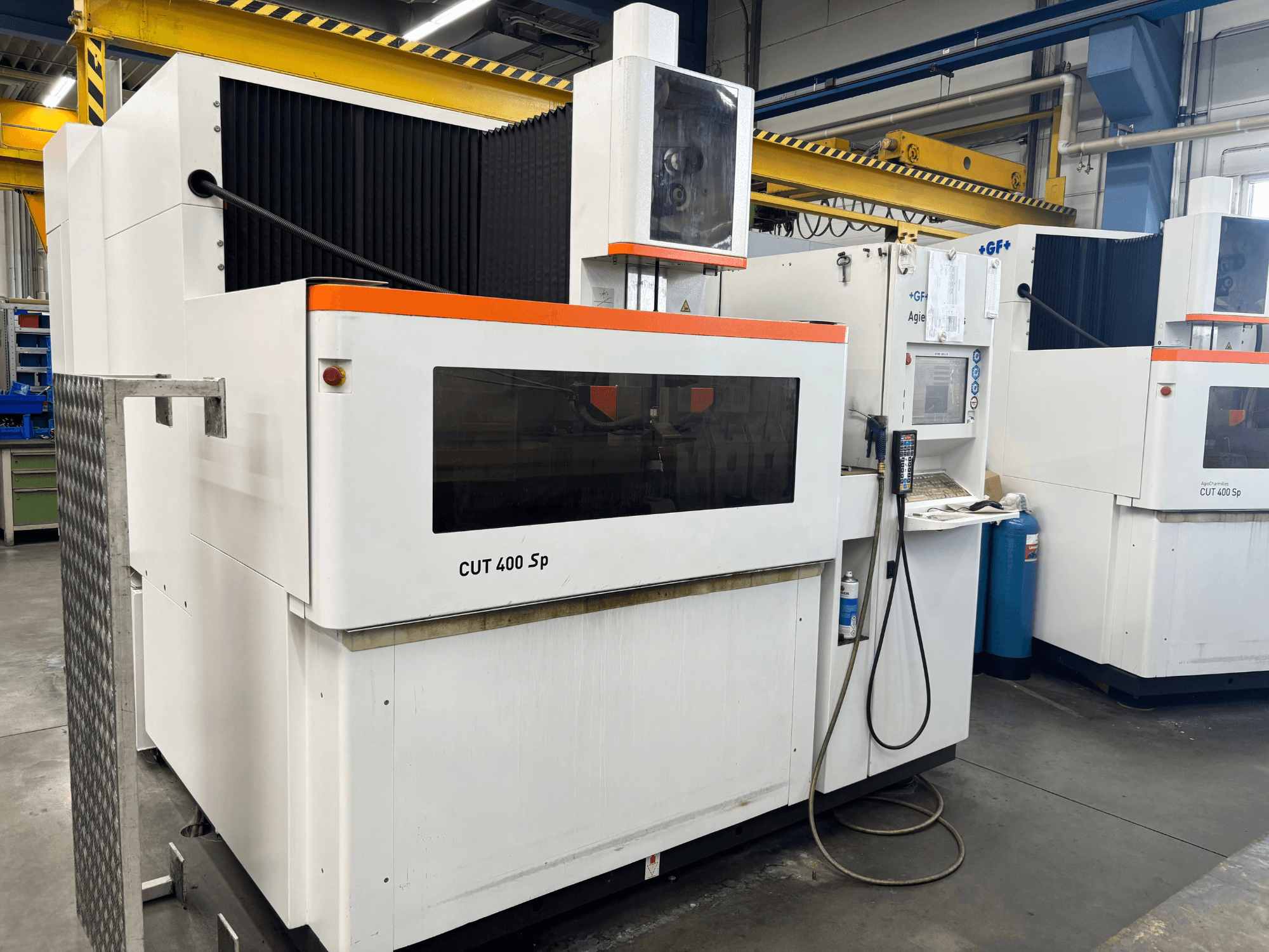 Draht-EDM-Maschine +GF+ AGIECHARMILLES CUT 400 Sp, Vorderansicht, mit Bedienfeld und angeschlossenem Kühlsystem.