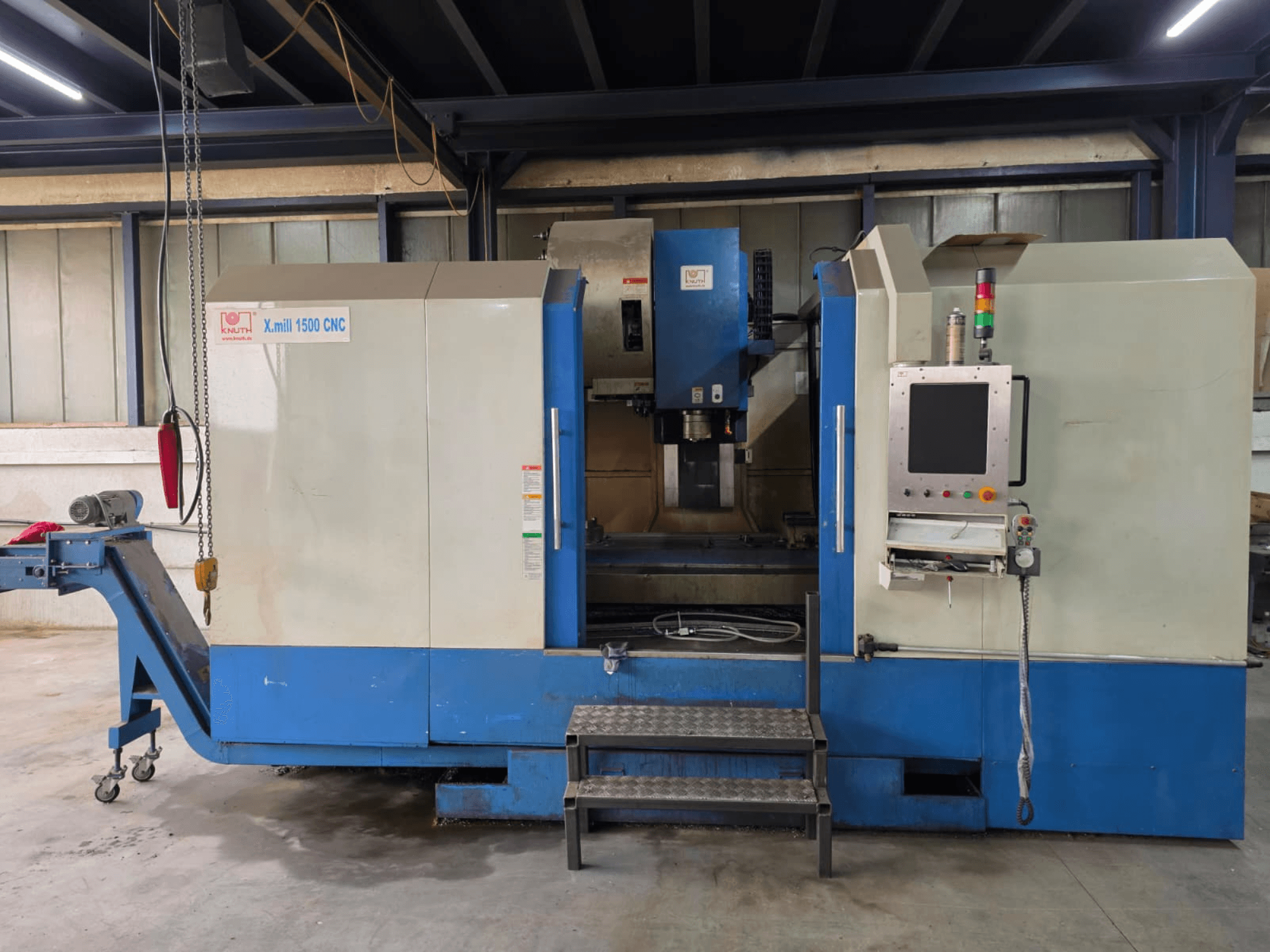 CNC-Vertikalbearbeitungszentrum KNUTH X-MILL 1500, Seitenansicht, mit Bedienfeld, Stufen und Auslaufband.