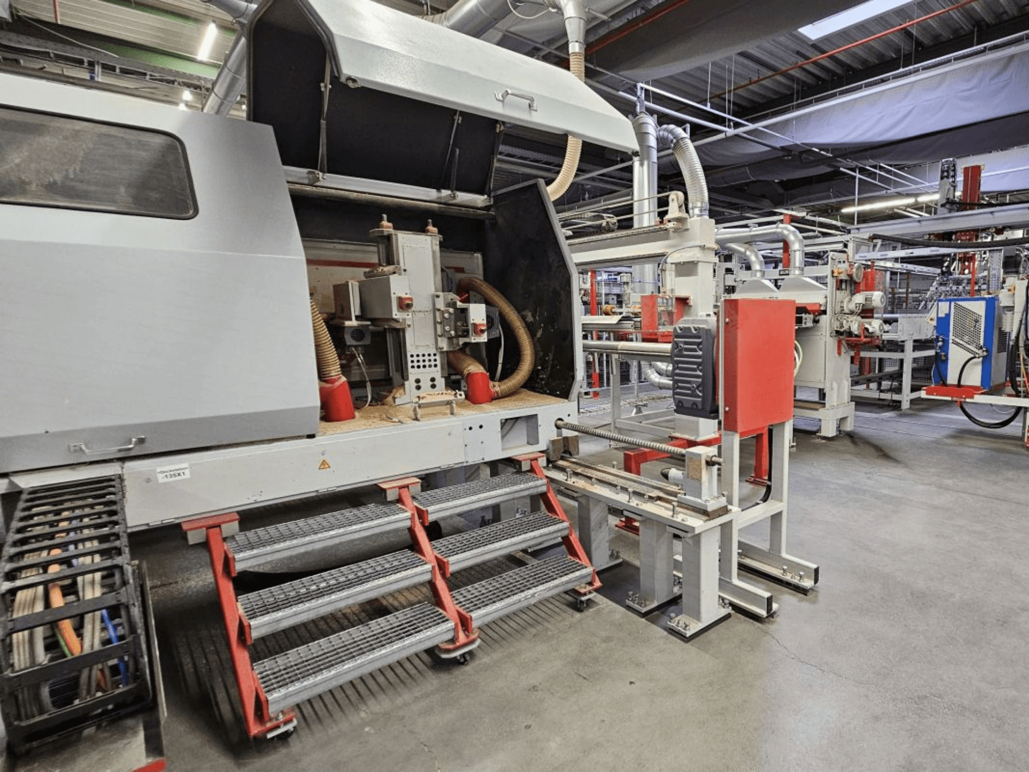 Frontansicht der BURKLE Optima 1428/50 Holzproduktionslinie mit Stufen und sichtbaren Maschinenkomponenten.