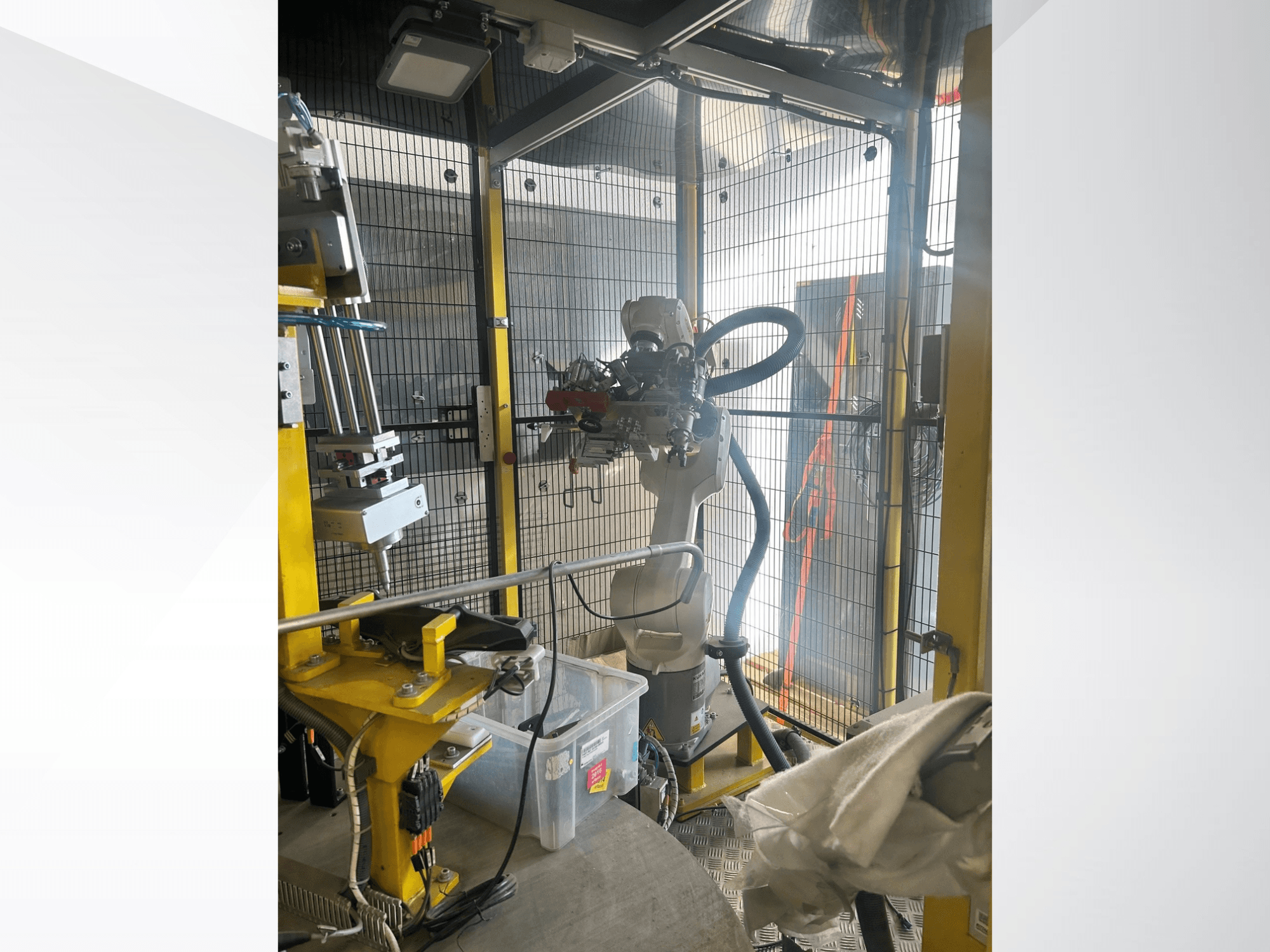 Roboterarm des MEI Automotive Automation System in einem gesicherten Gehäuse, Vorderansicht, mit mechanischen Komponenten und Bedienelementen.