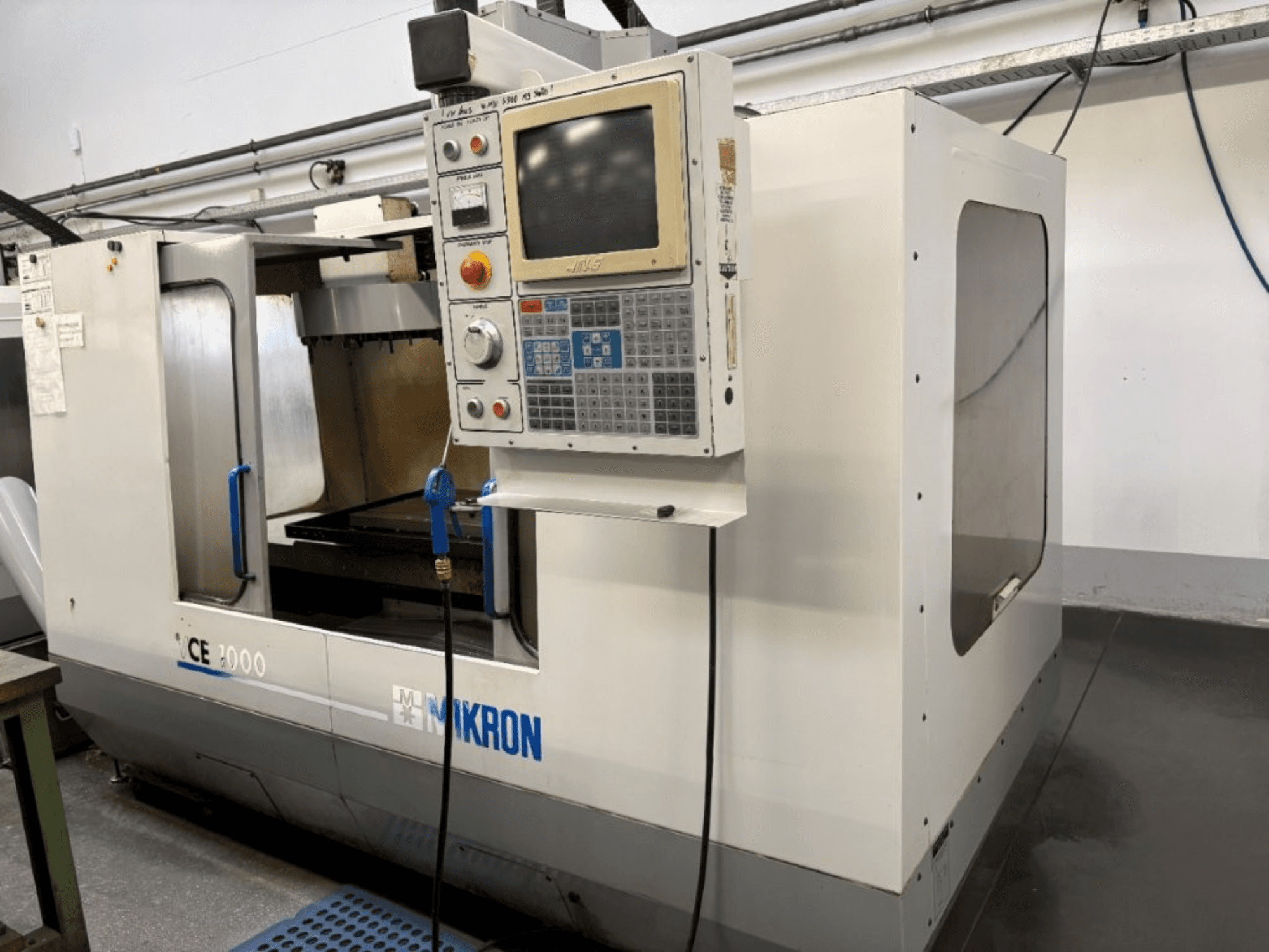 Mikron CE 2000 CNC-Maschine, Vorderansicht; mit Bedienfeld mit Tasten und Bildschirm, silbernem Gehäuse und Arbeitsbereich.