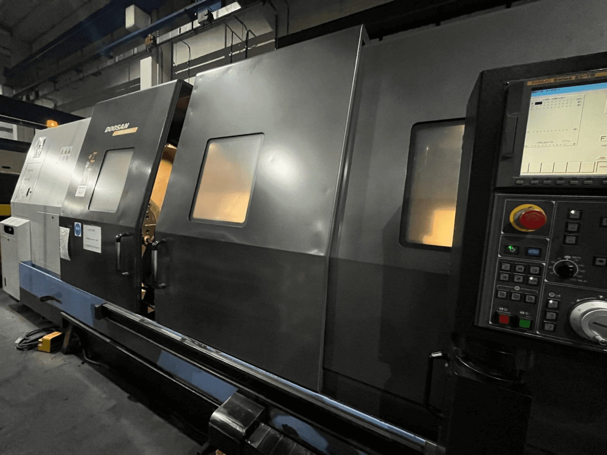 Doosan-CNC-Drehmaschine in der Vorderansicht, mit Bedienfeld und Bedienerschnittstelle mit sichtbarer Digitalanzeige und Tasten.