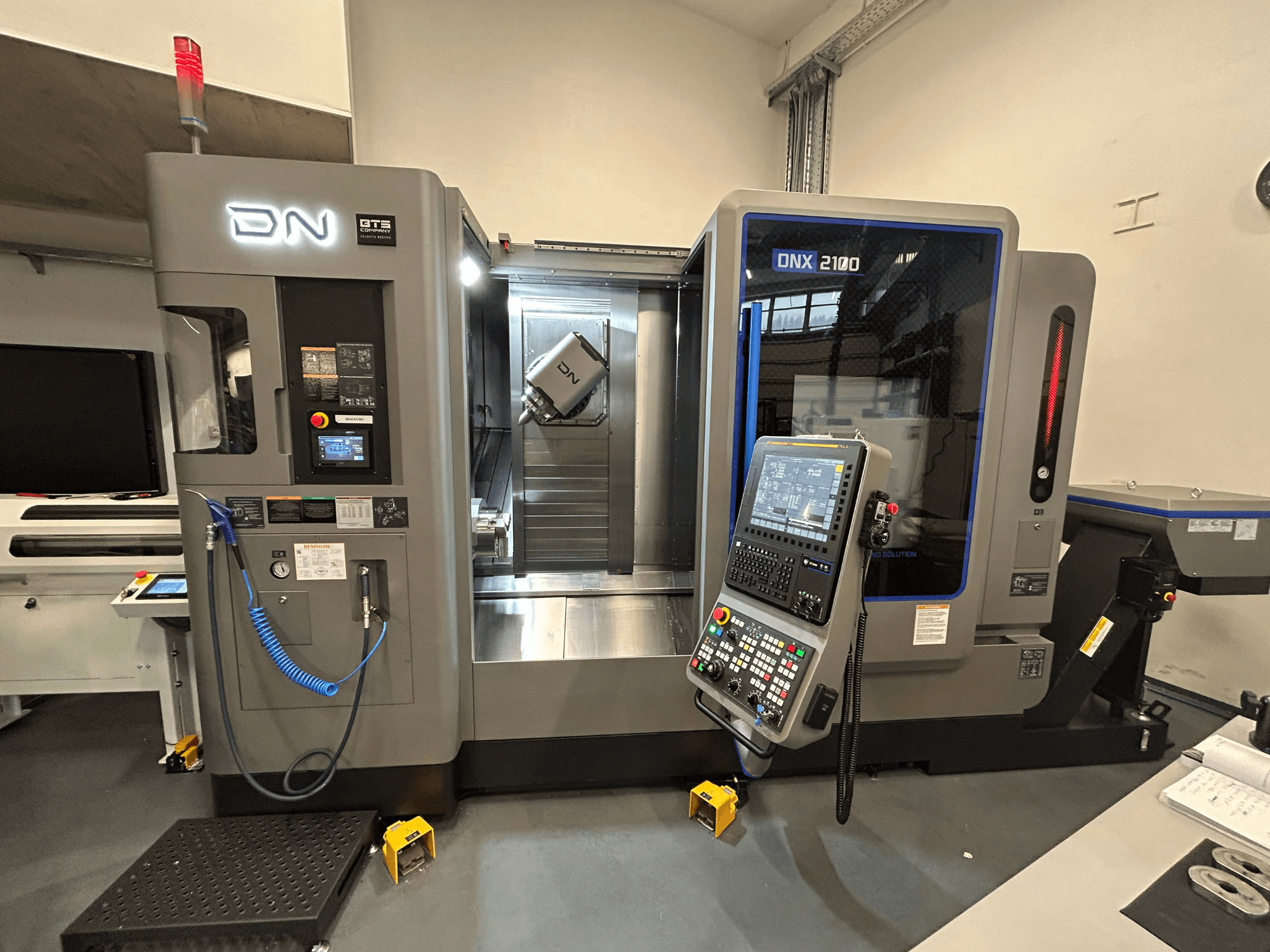 CNC-Maschine DN ONX 2100, Vorderansicht, mit Bedienfeld, Arbeitsbereich und Werkzeug. Ausgestattet mit Sicherheitslicht und Betriebsanzeigen.