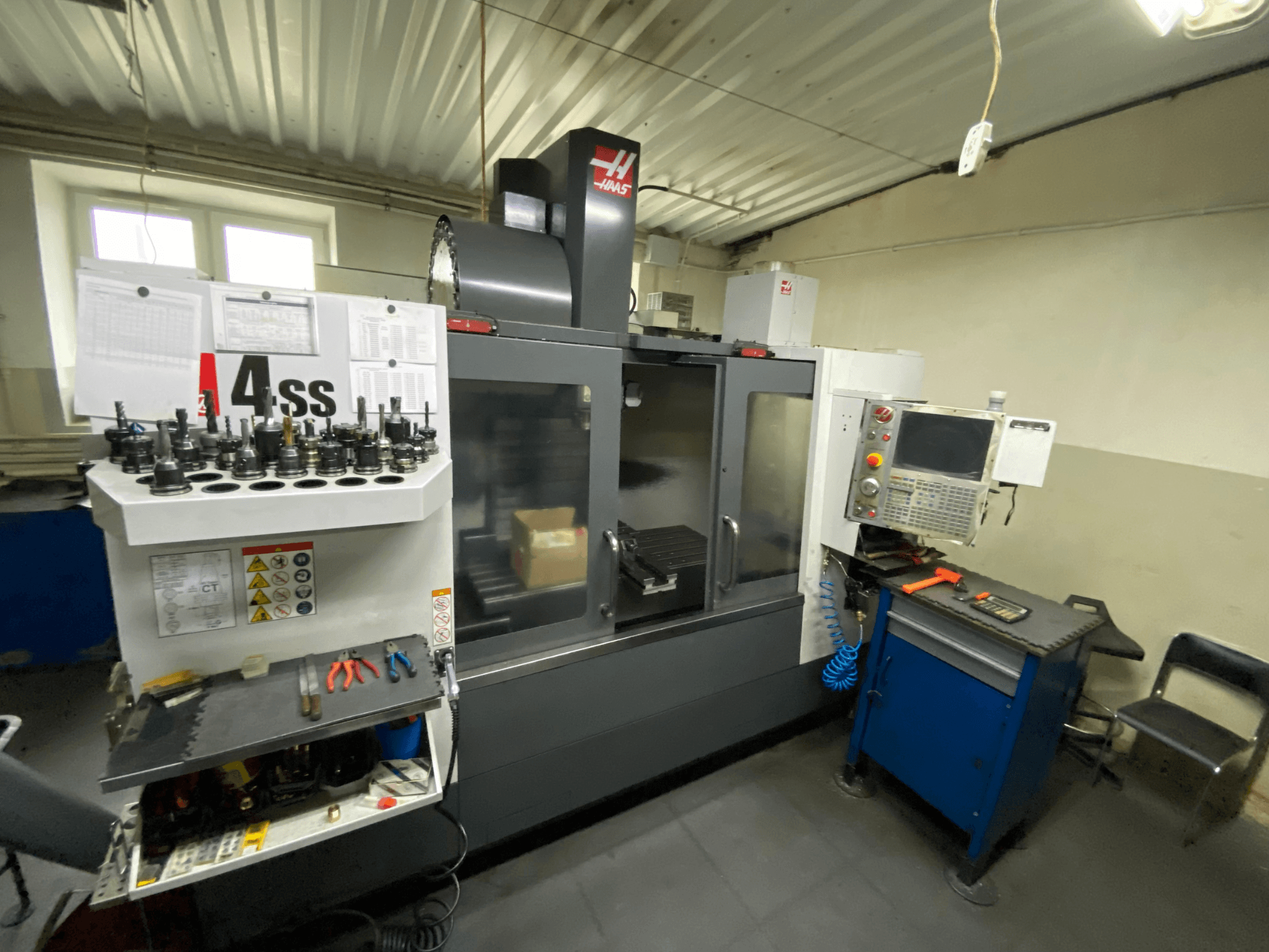 Vertikales Bearbeitungszentrum Haas VF-4SS, Vorderansicht mit Werkzeughaltern und Bedienfeld. Die verwendeten Werkzeuge und der Arbeitsbereich sind zu sehen.