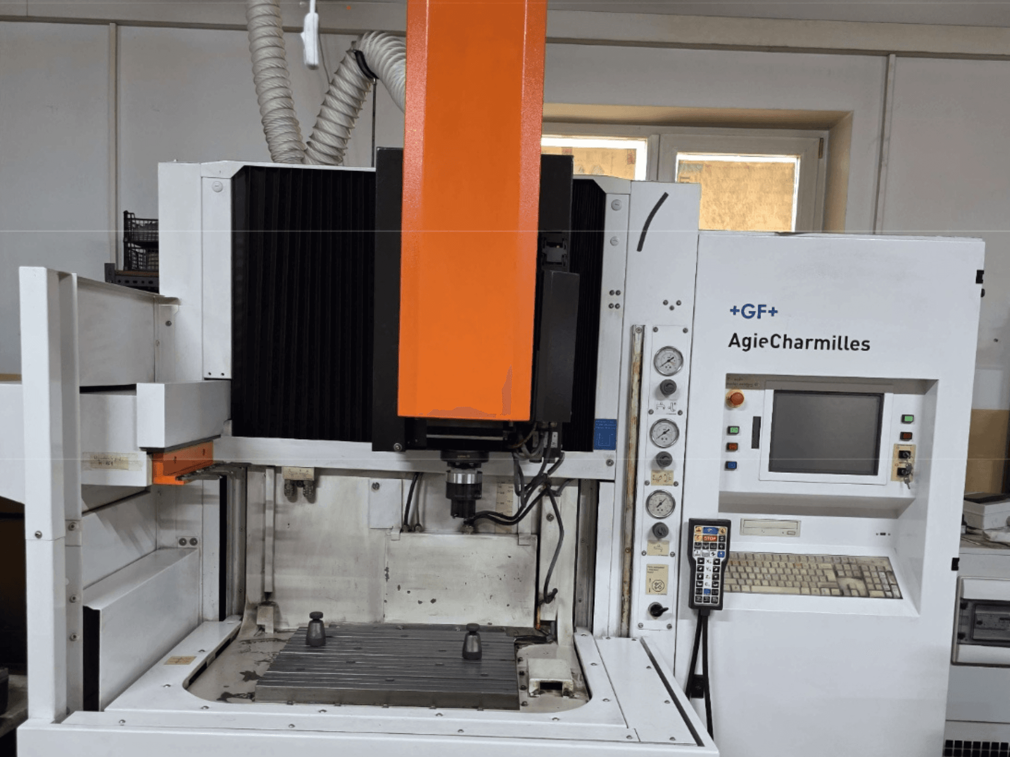 AgieCharmilles Bearbeitungszentrum in der Vorderansicht mit großer orangefarbener Spindel, Bedienfeld und sichtbarem Arbeitstisch.