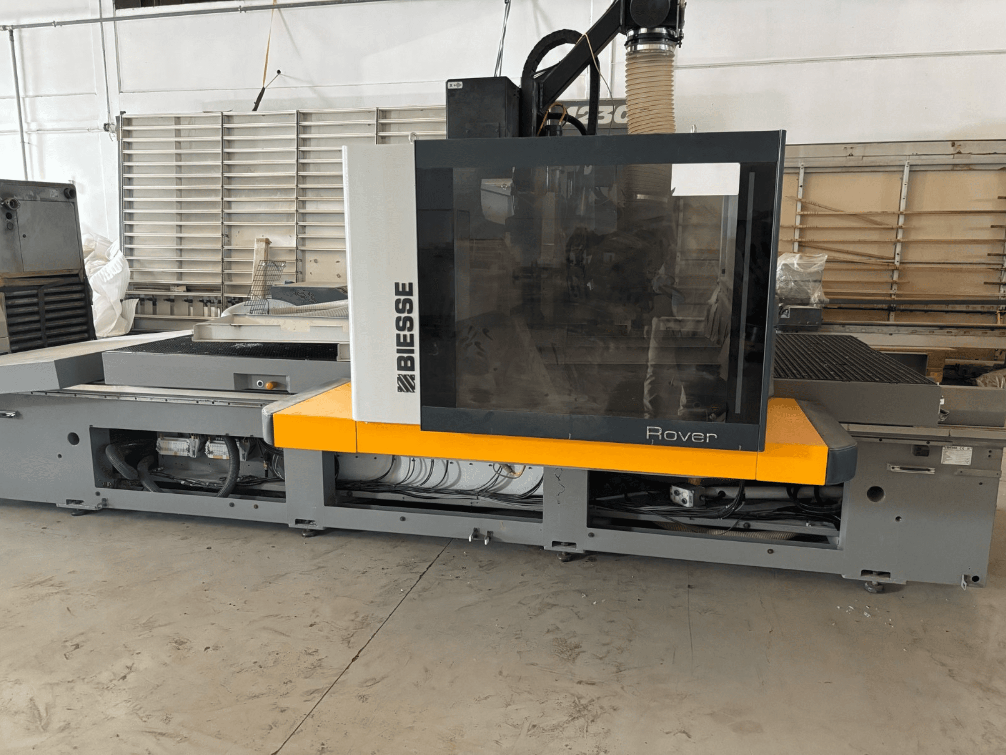 Biesse Rover CNC-Bearbeitungszentrum, Vorderansicht, mit großem Bedienfeld, gelben Akzenten und freiliegenden mechanischen Komponenten.