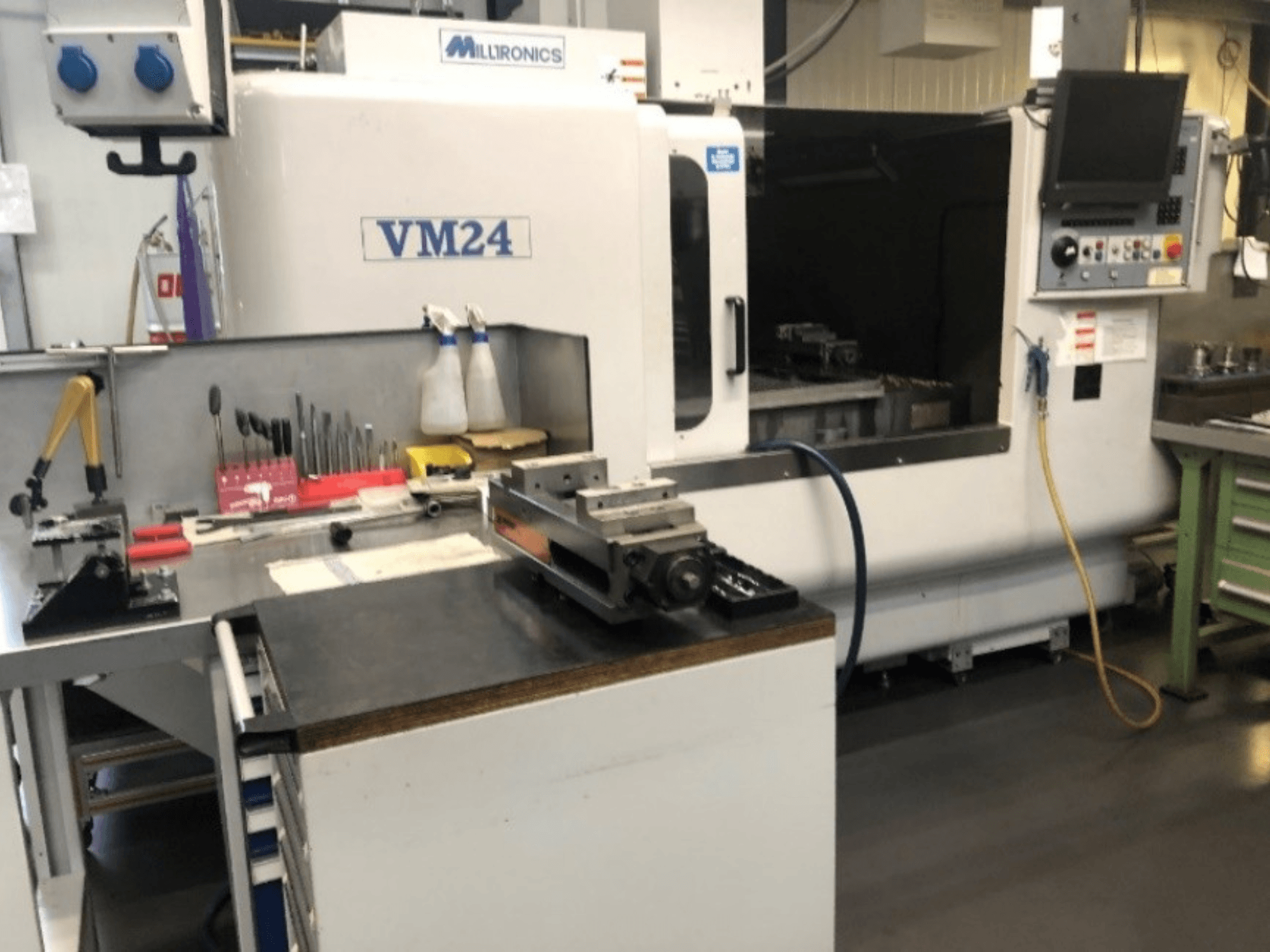 Maschinenarbeitsplatz mit der CNC-Maschine Milltronics VM24. Vorderansicht mit Werkzeugen und Ausrüstung auf einer Werkbank.