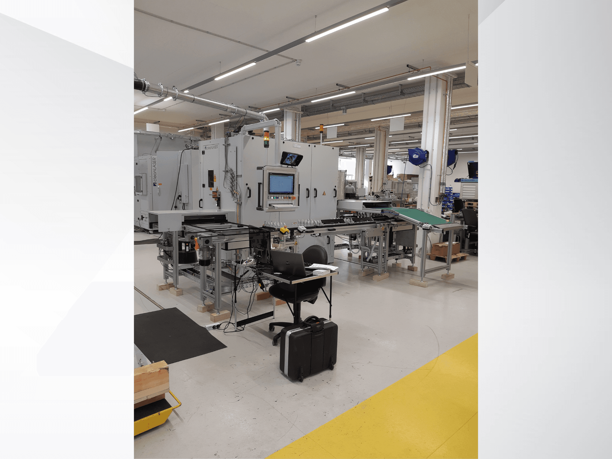 CLEAN LASER clean CELL 3220 Werkzeugmaschine, Vorderansicht mit Bedienfeld, Förderband und Arbeitsstation in einer Fabrikumgebung.