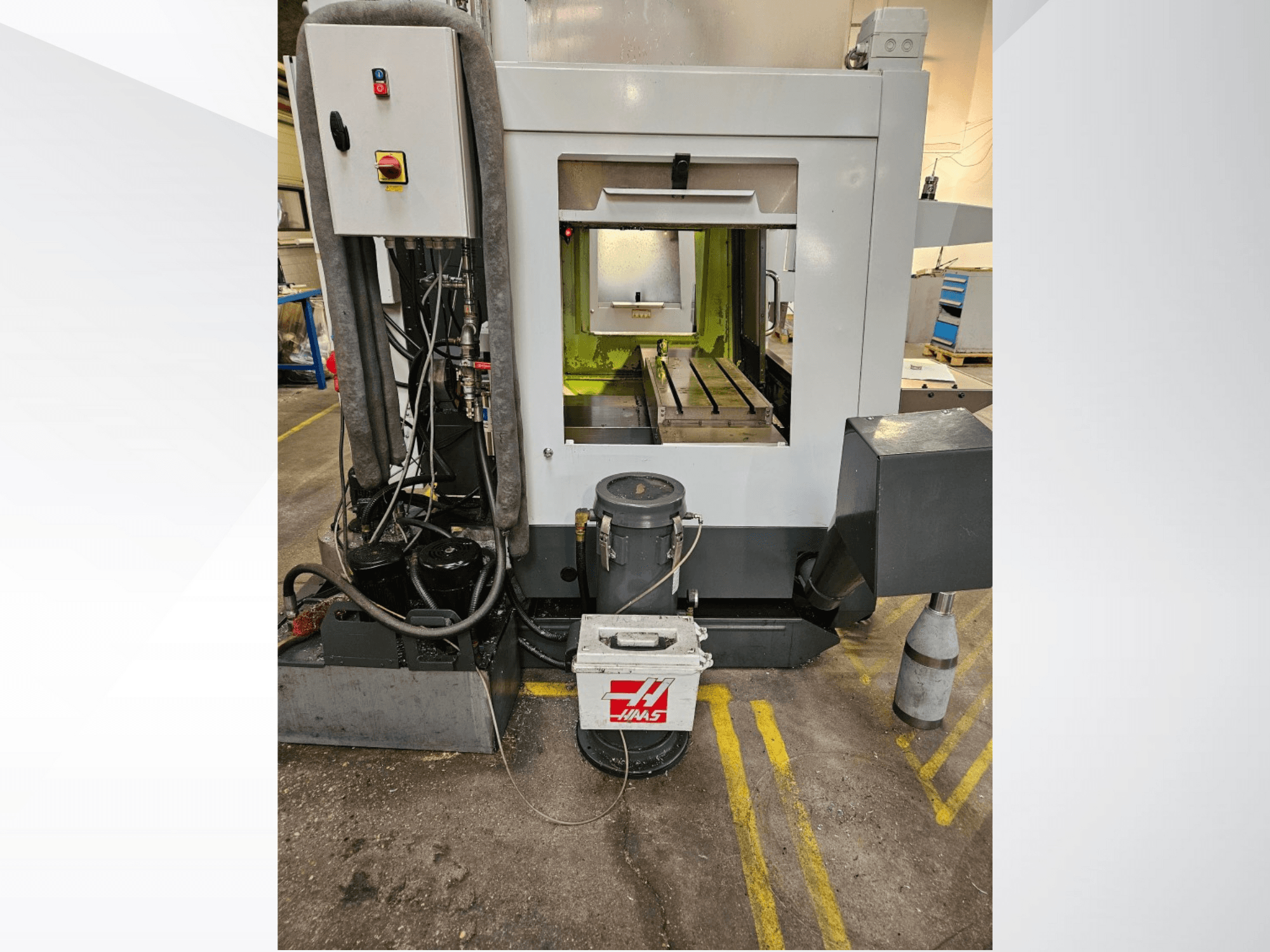 Frontansicht der Haas CNC-Maschine mit Bedienfeld, Kühlmittelbehälter und bearbeitetem Bett in der Ausstellung.