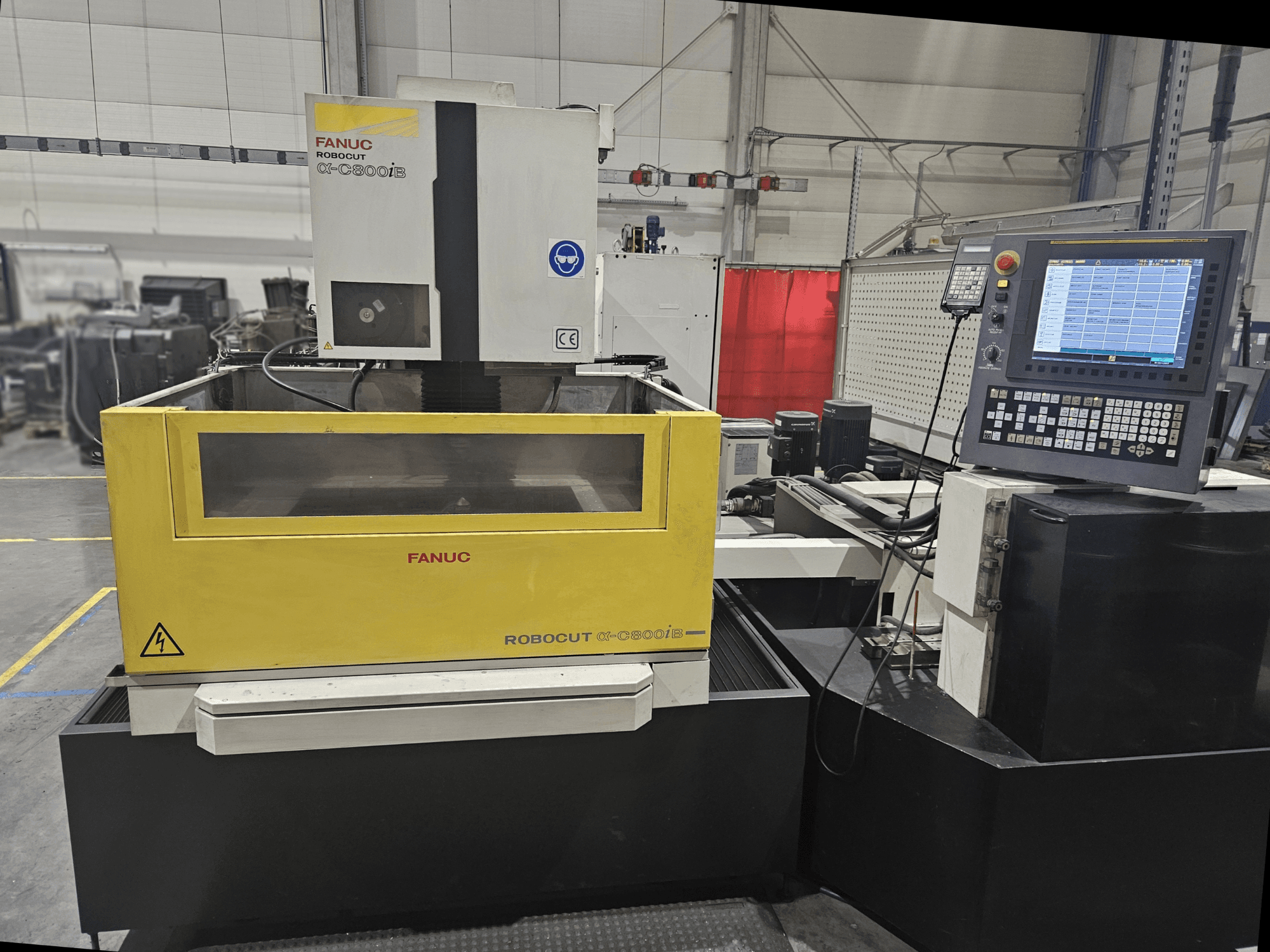 Vorderansicht des FANUC Robocut α-C600iB mit gelbem und grauem Maschinengehäuse, CNC-Bedienfeld und Betriebsanzeige.