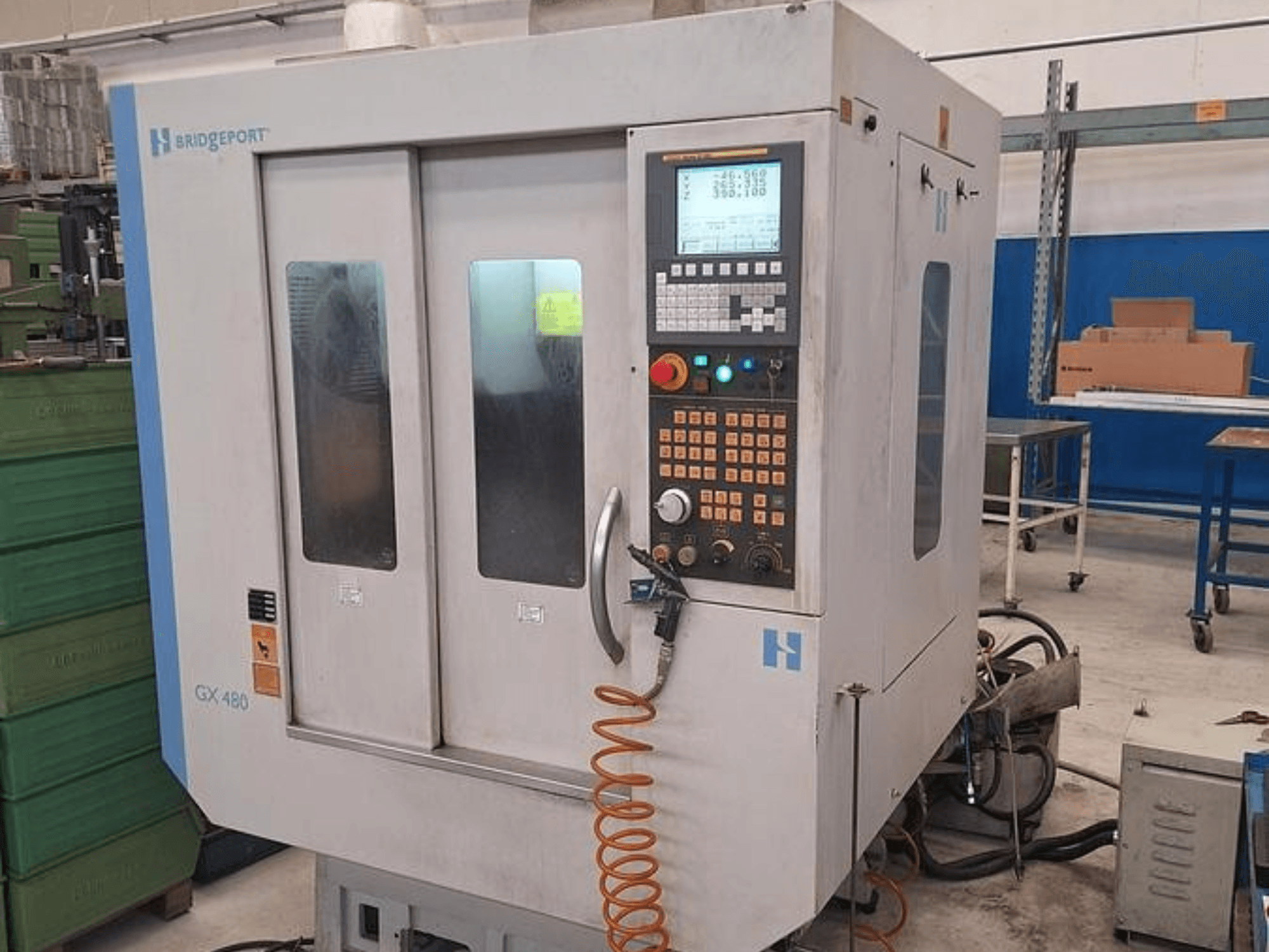 Vertikales Bearbeitungszentrum Bridgeport GX 480 in der Vorderansicht, mit Bedienfeld, zwei Glastüren und flexiblem Schlauch.